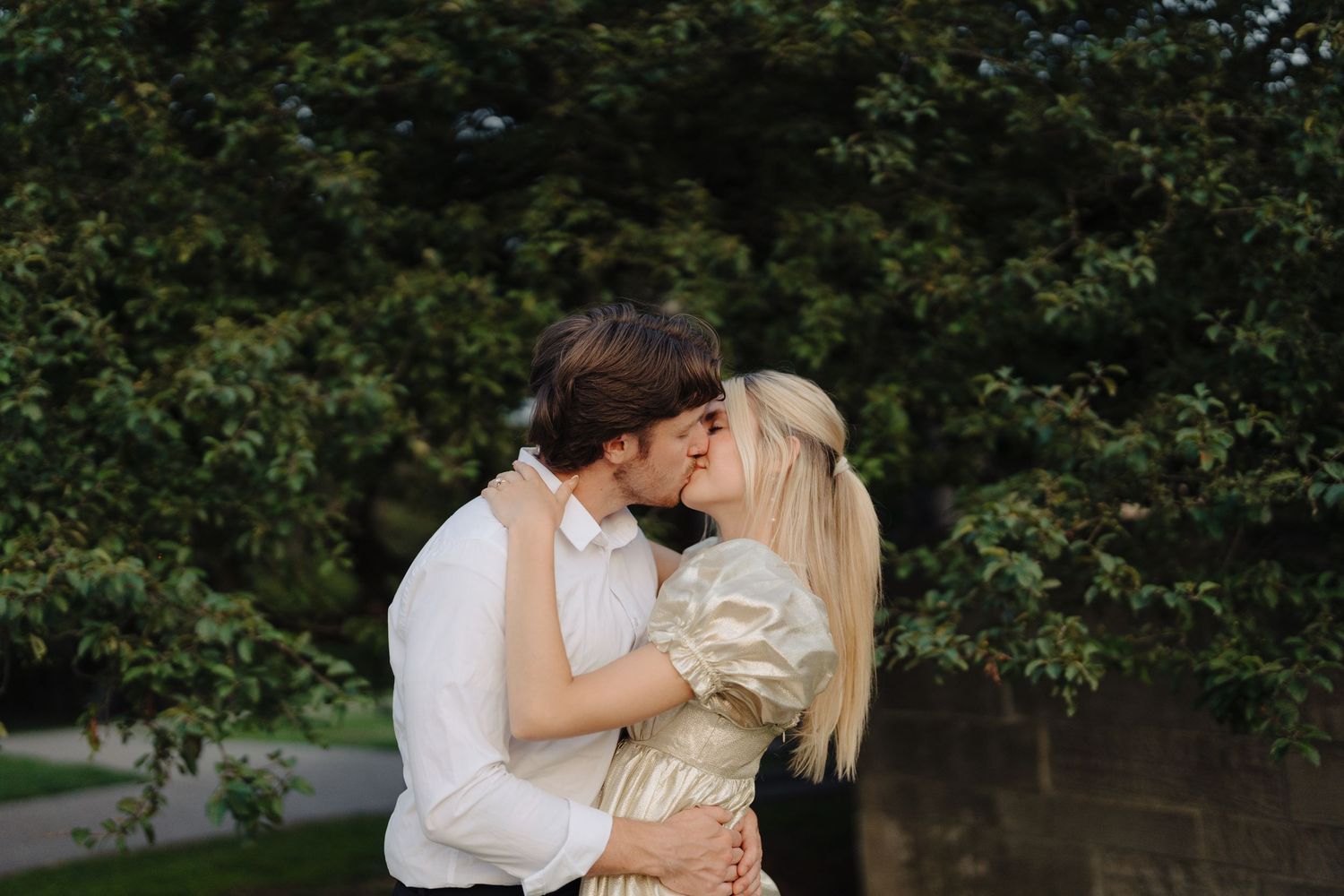 Intimate couple portrait against lush green garden backdrop.