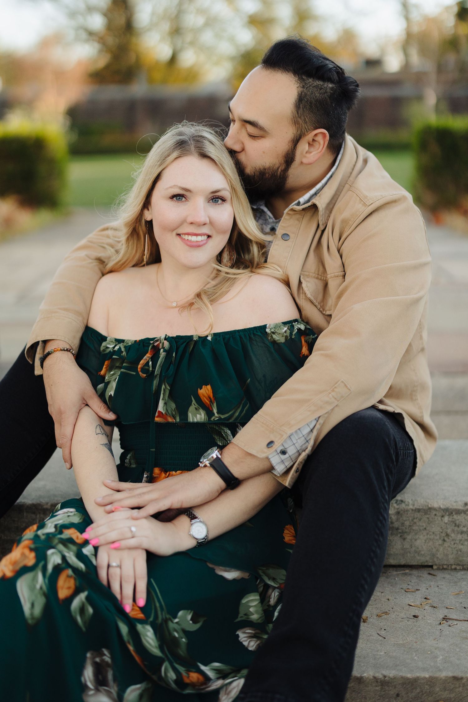 A romantic couple shares tender moments while sitting together during an autumn outdoor photoshoot.