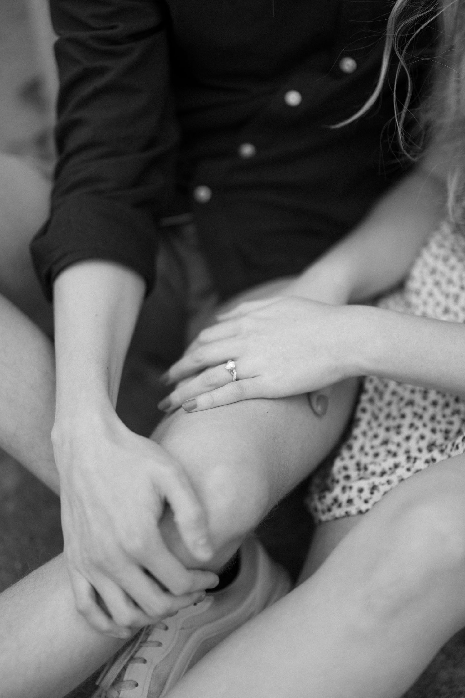 Close-up black and white photo showing hands and engagement ring.