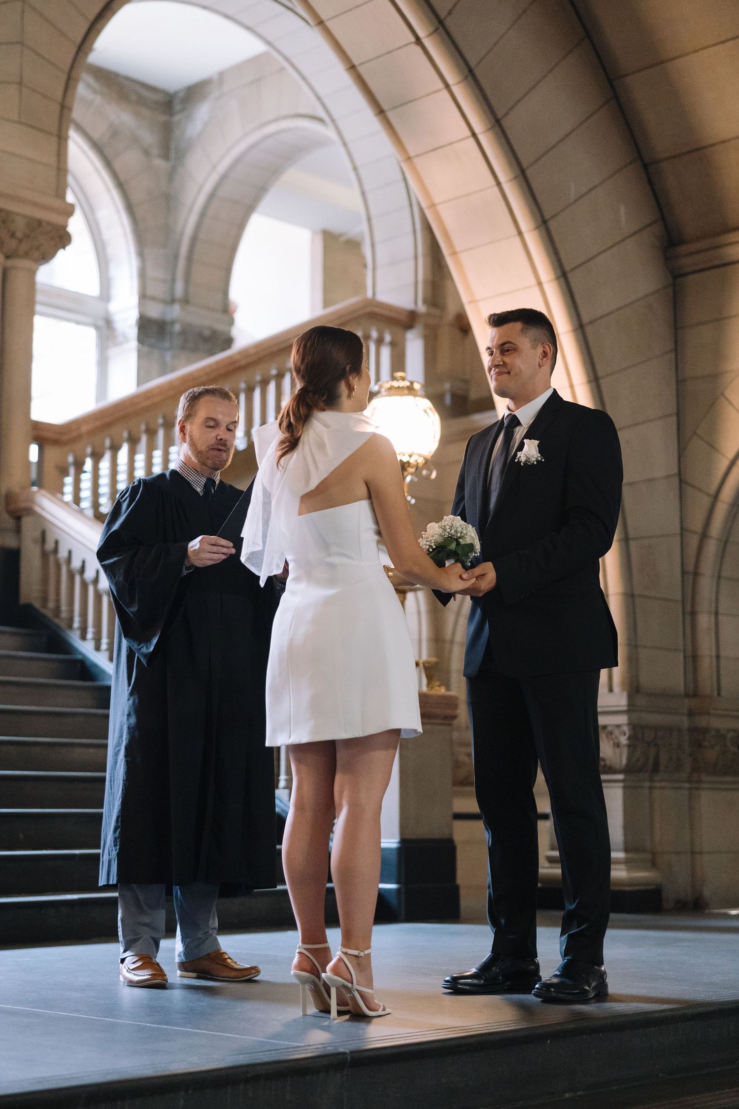 An intimate wedding ceremony taking place on stone steps with arched architectural details.