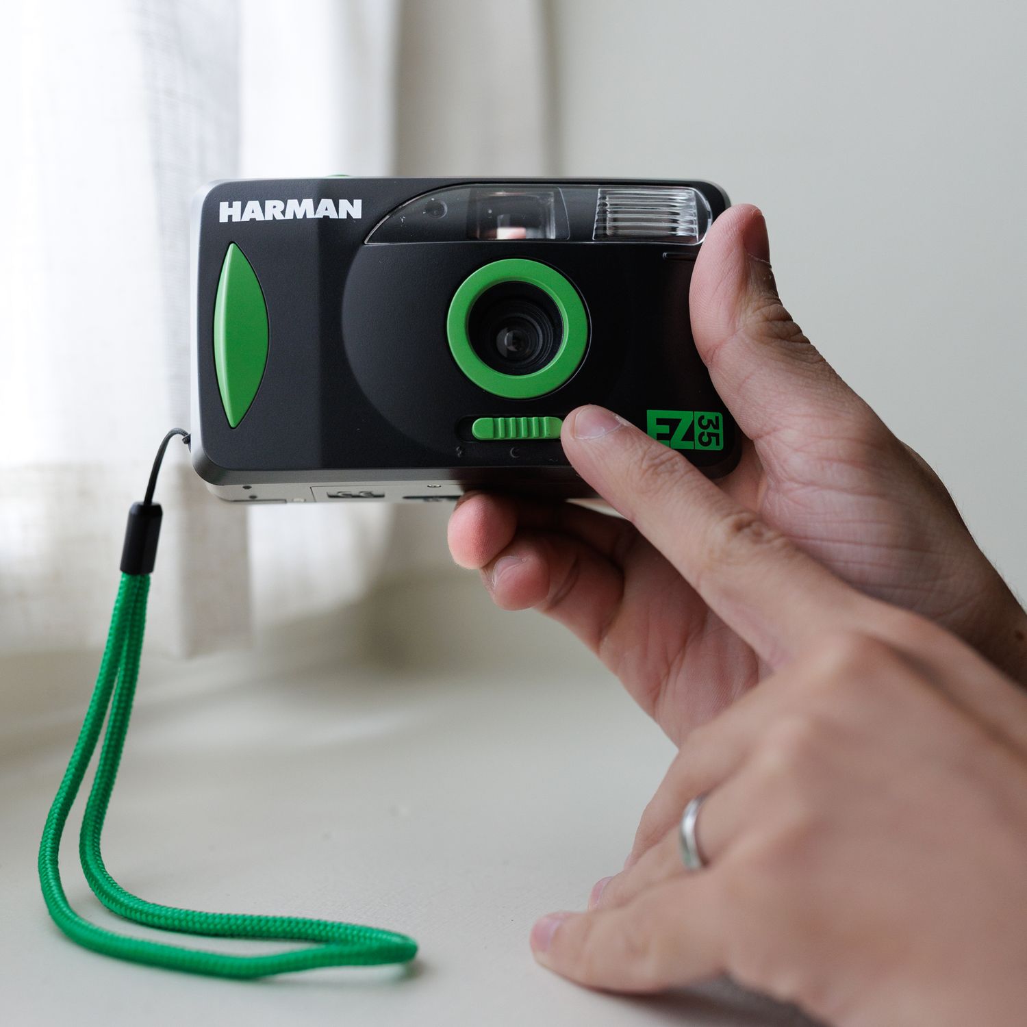 Black wireless webcam with neon green accent cord shown from multiple angles on white background.