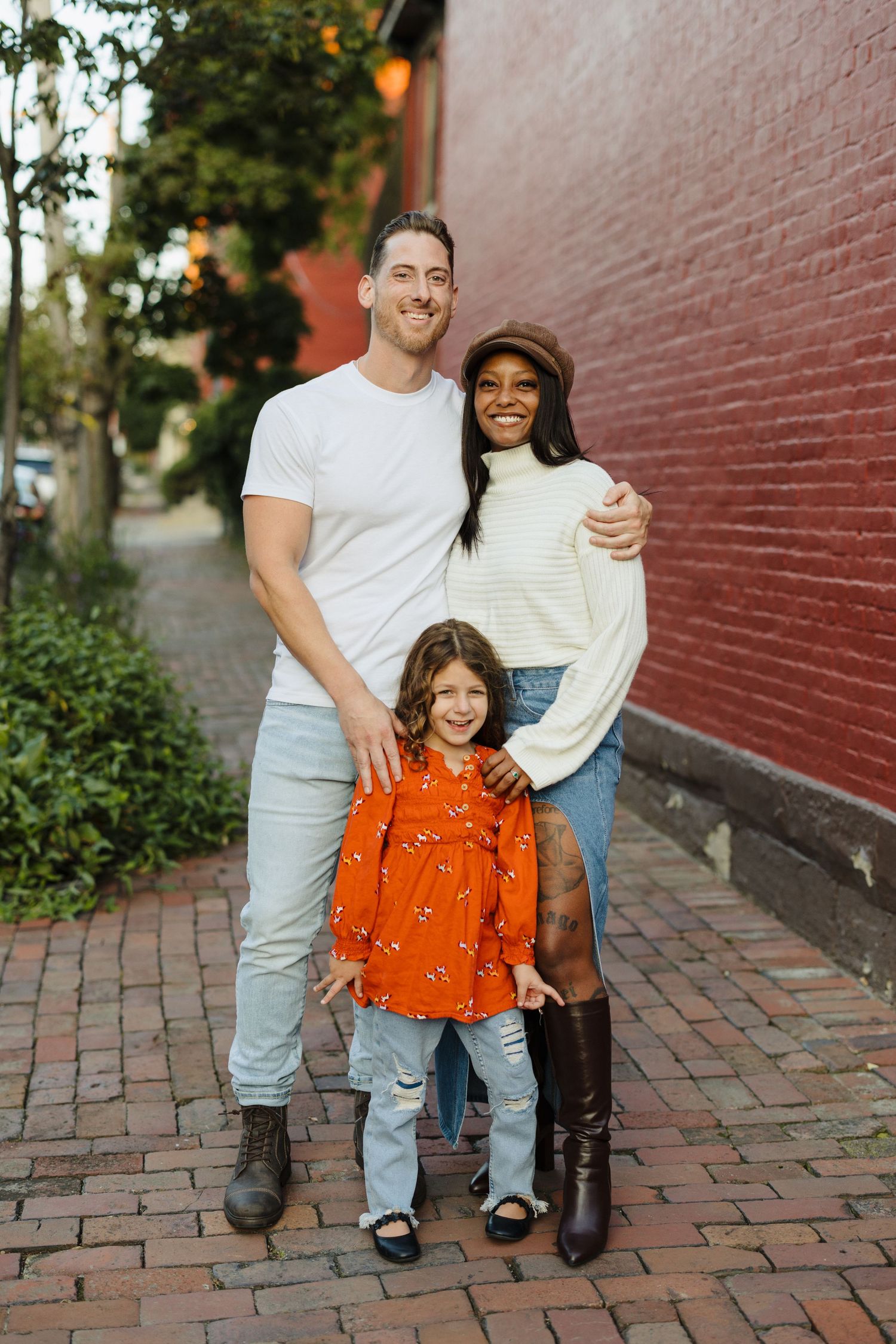 Family photoshoot shows intimate portraits on brick sidewalk with coordinated casual outfits in an urban outdoor setting.