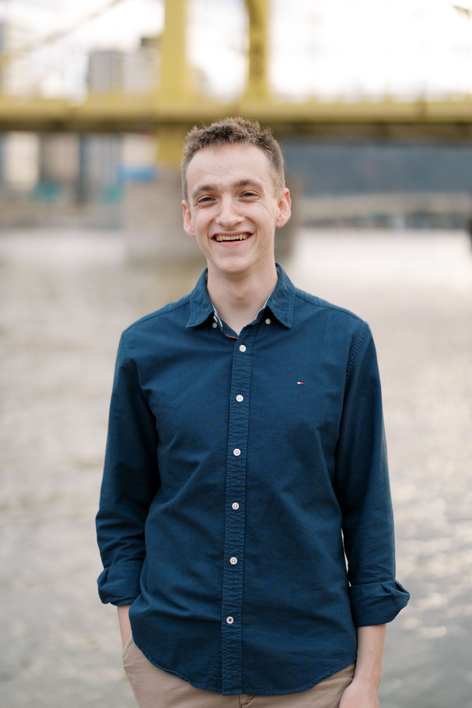 A casual portrait on a pier with a navy button-down shirt against an urban backdrop.