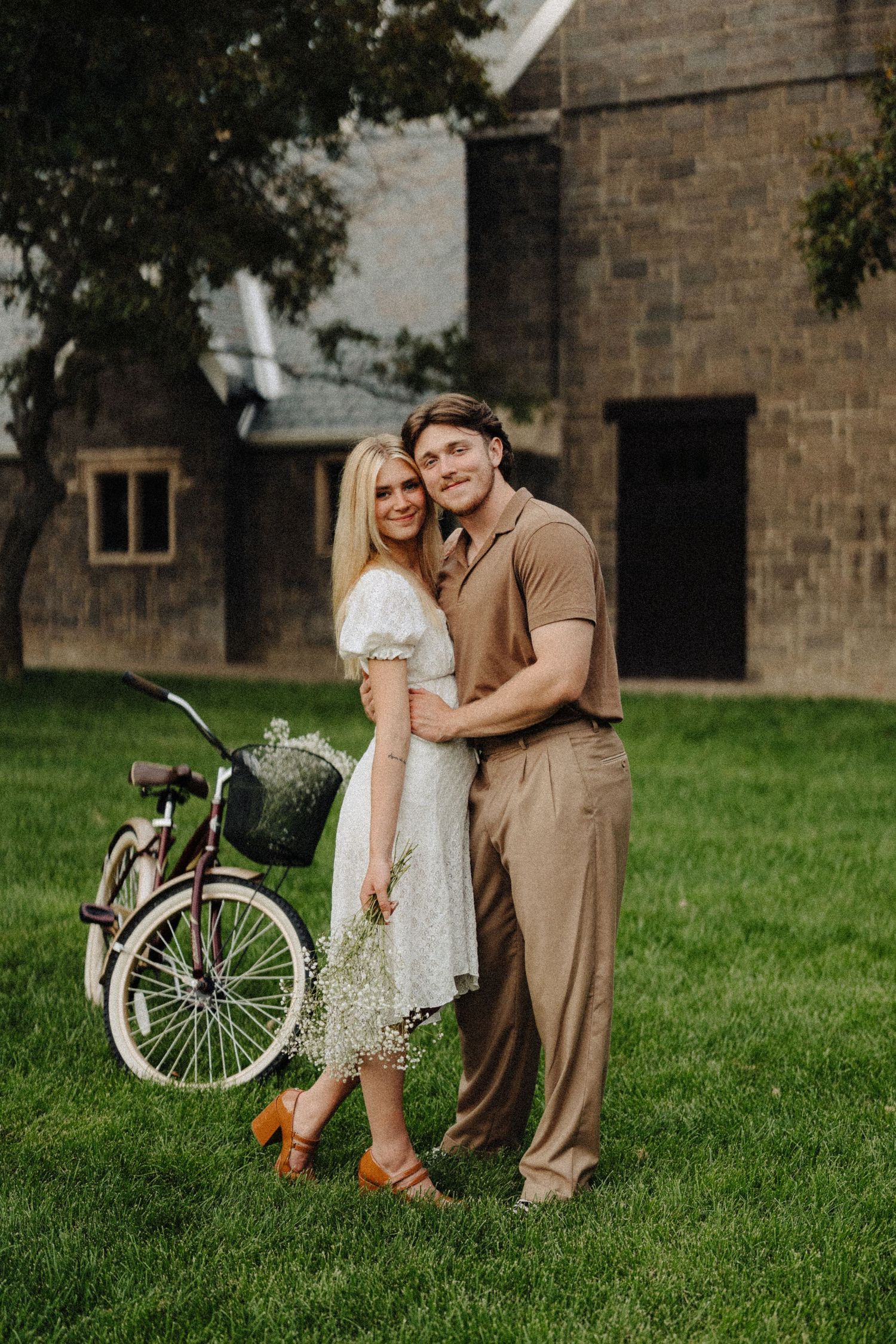 A vintage-inspired portrait beside an old stone building with a classic bicycle as a prop.