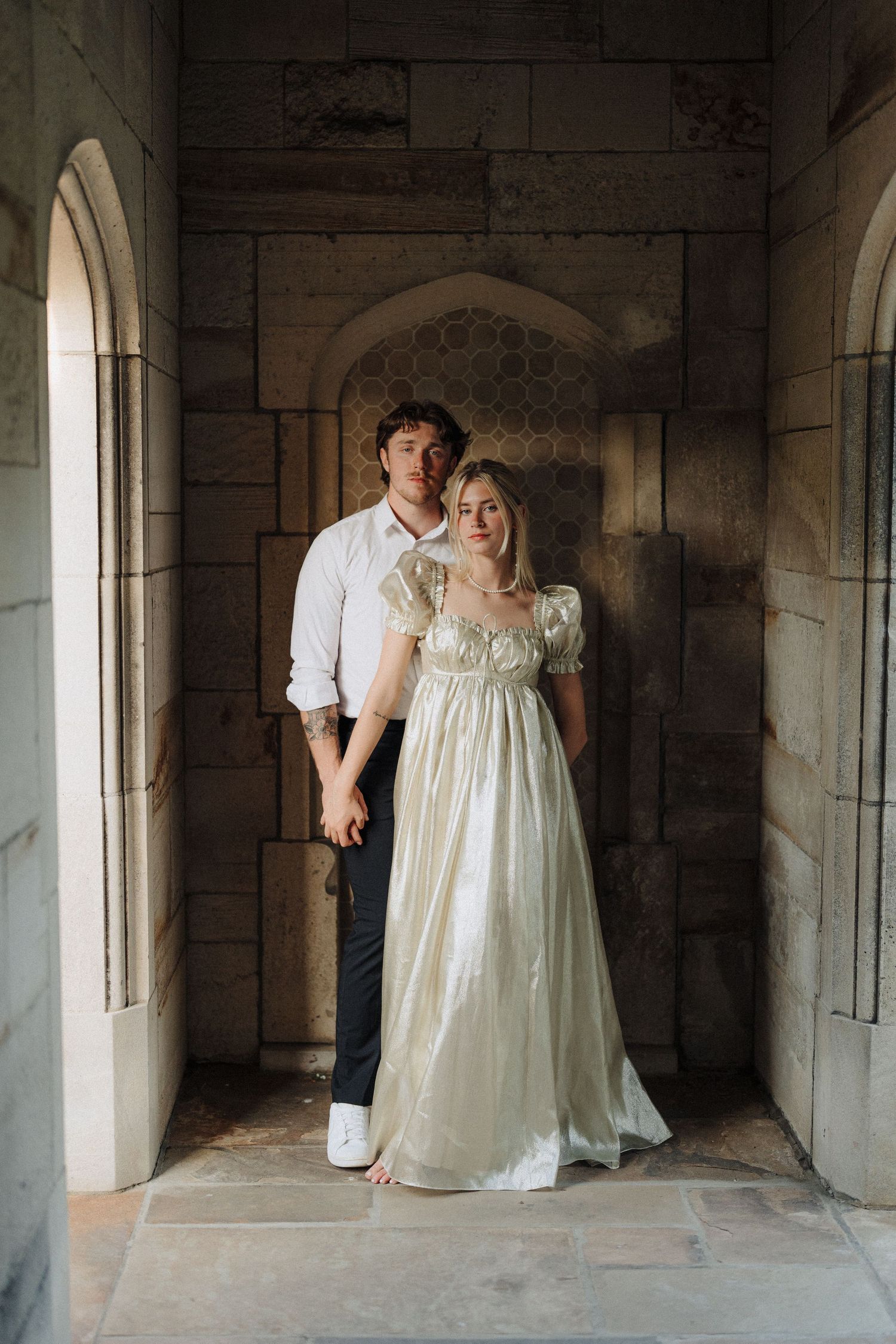 Classic couple portrait in stone archway with natural lighting.