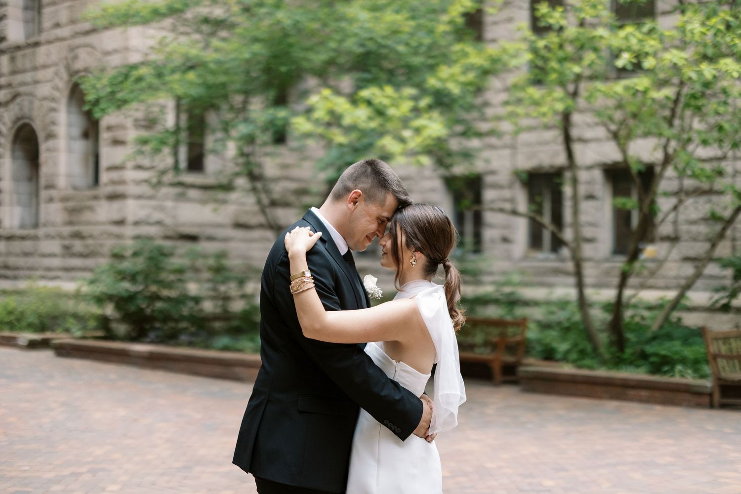 A couple embraces while dancing in a courtyard surrounded by stone architecture.