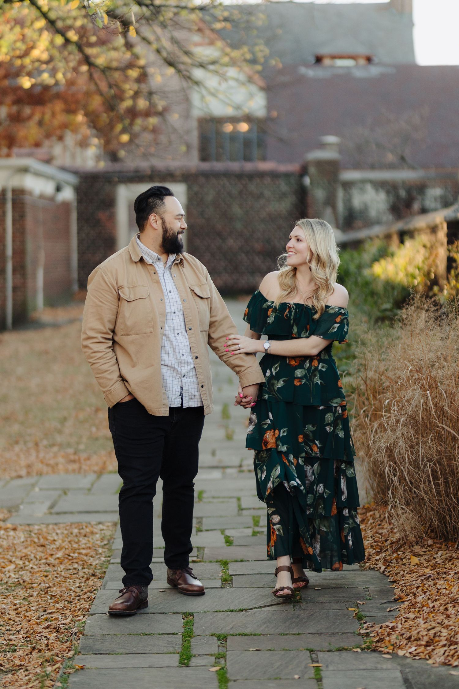 Couple walking on autumn pathway surrounded by fallen leaves enjoys intimate moments in golden sunlight.
