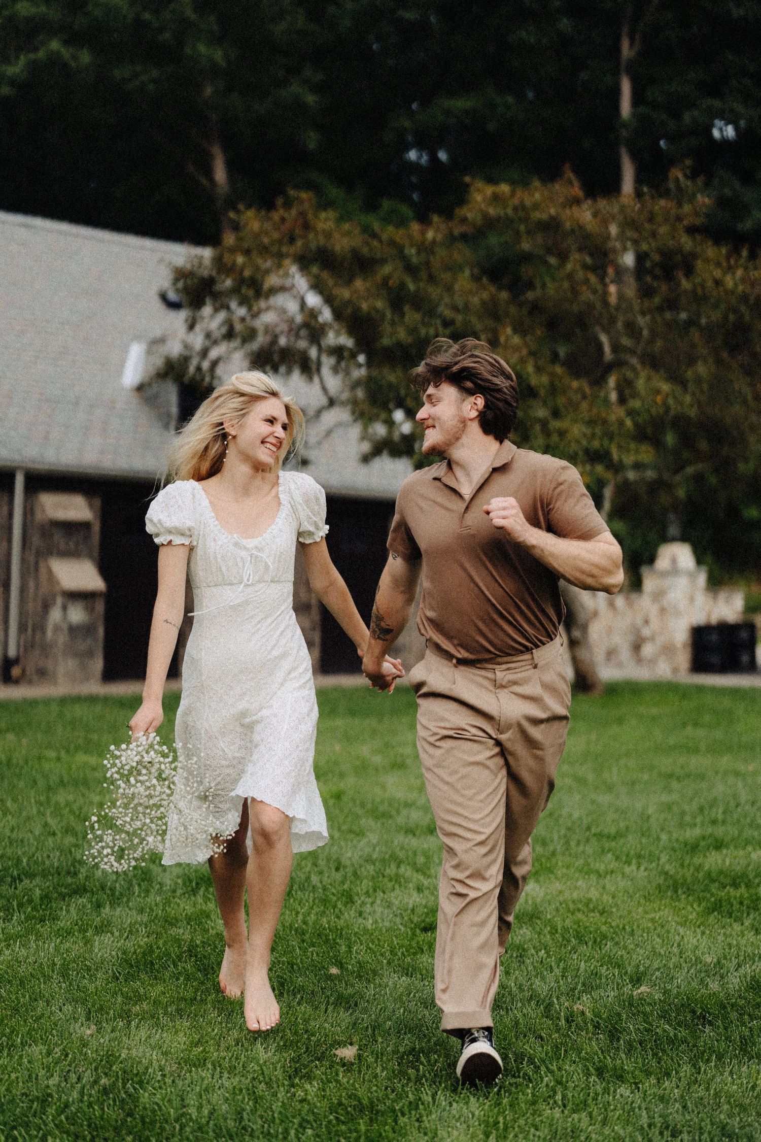 Running through a grassy field with baby's breath flowers near a rustic barn setting.
