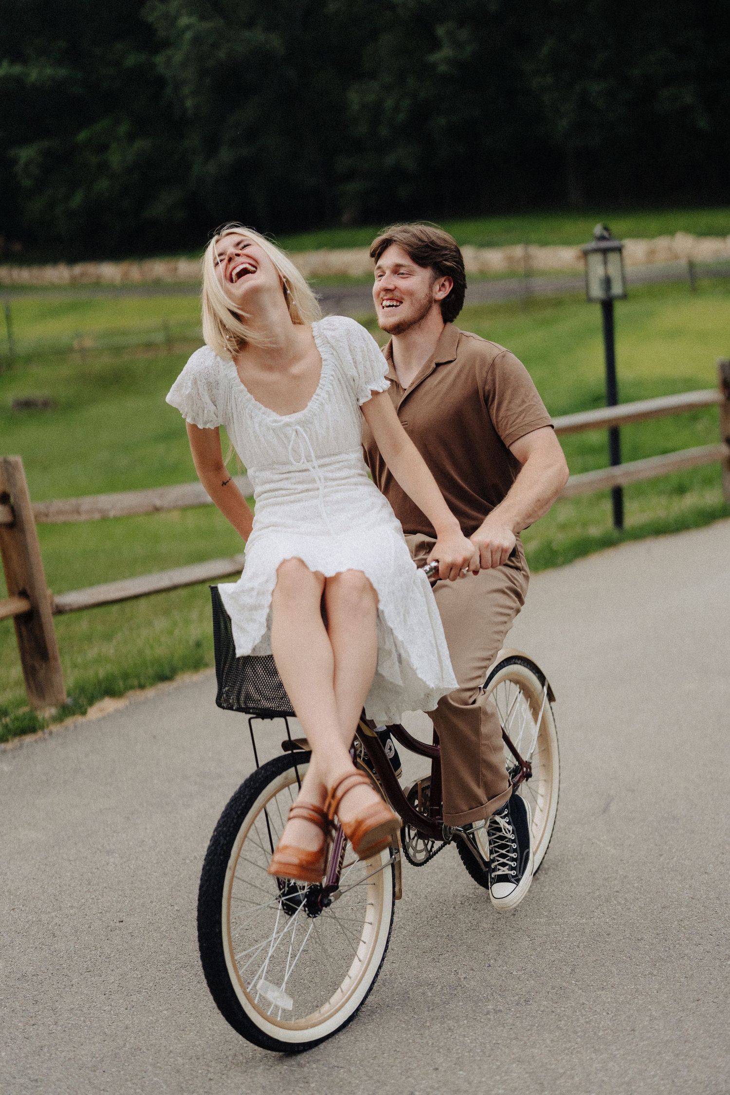 A joyful bicycle ride together on a path surrounded by green countryside and wooden fencing.