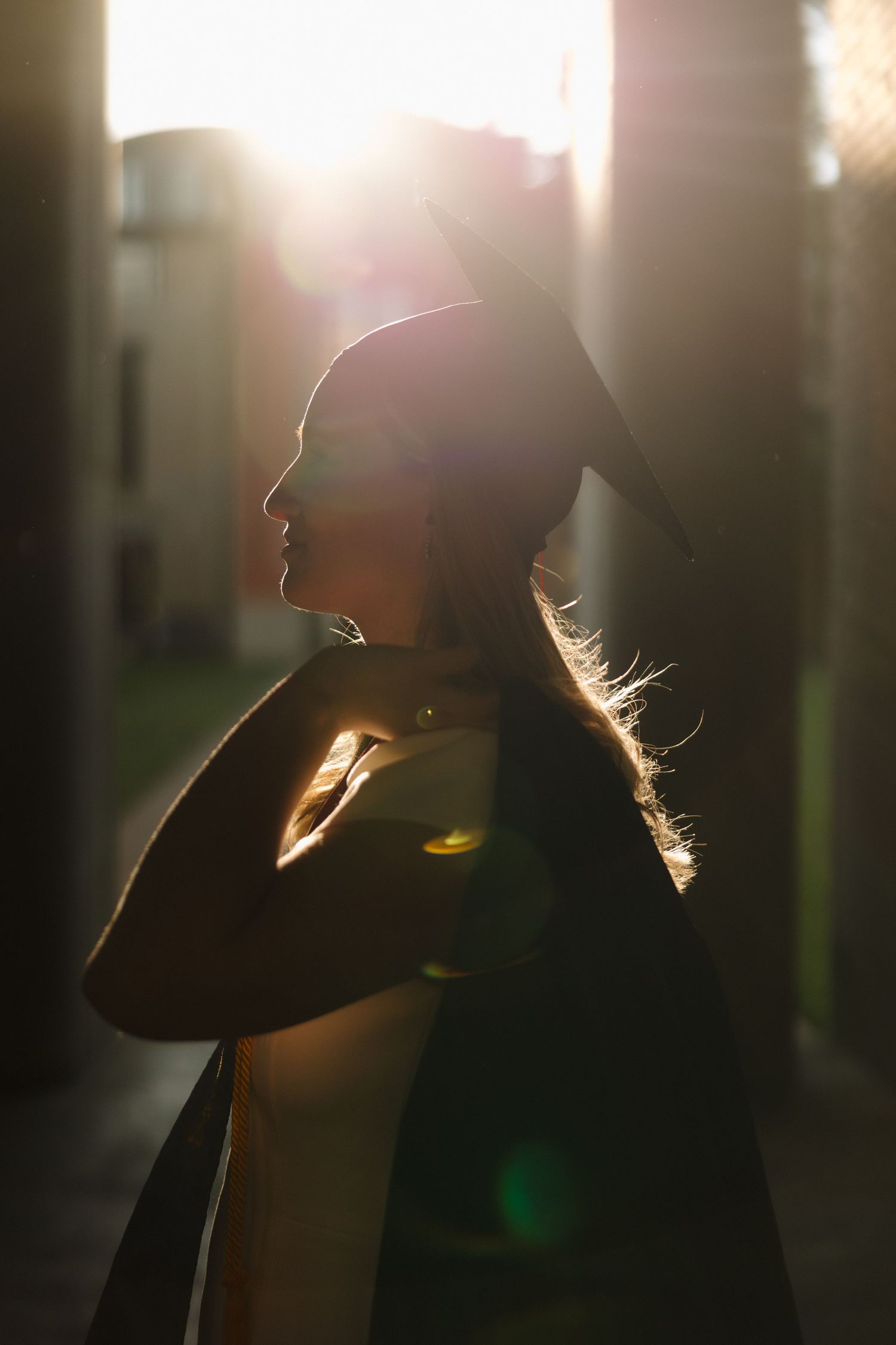 A silhouetted figure stands in dramatic backlit sunlight creating a golden glow around their profile.