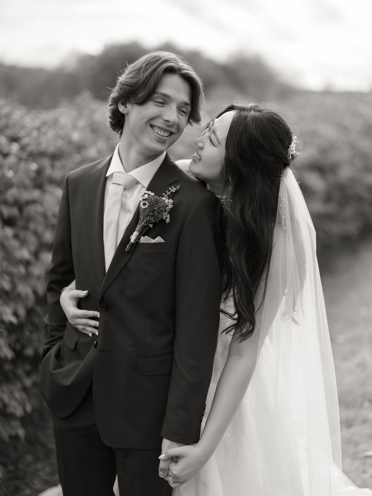 A romantic black and white photo series showing a bride and groom embracing and laughing together in an outdoor setting.