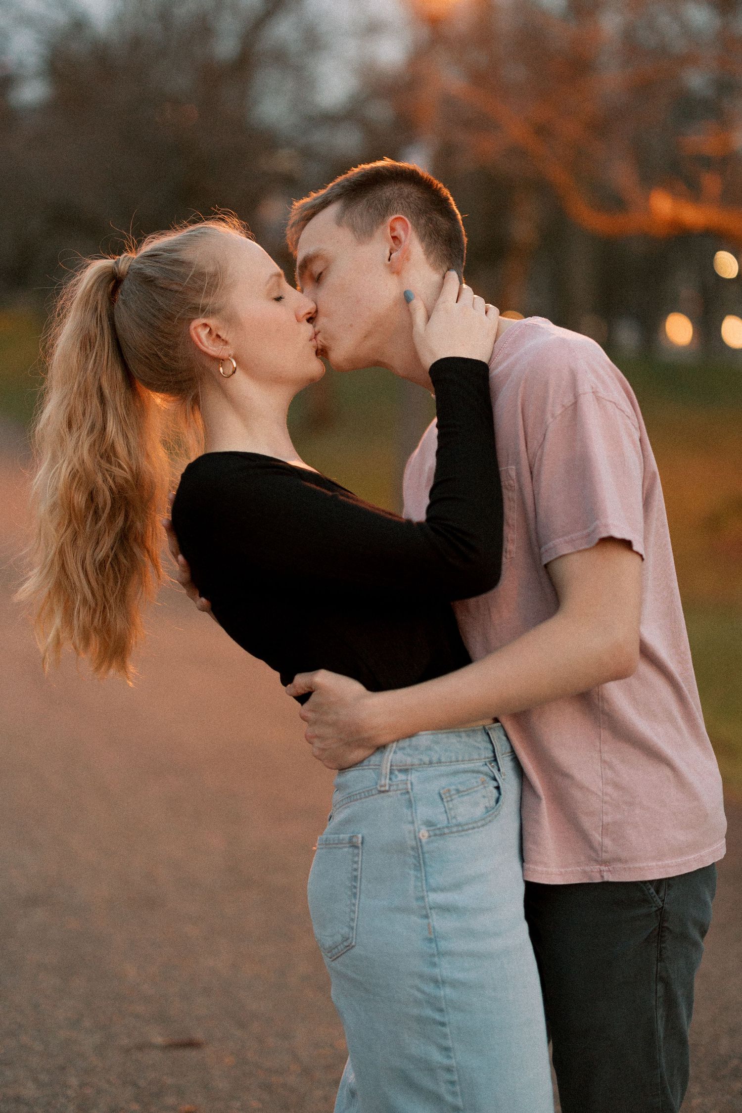 A tender sunset moment between a couple on a park path.