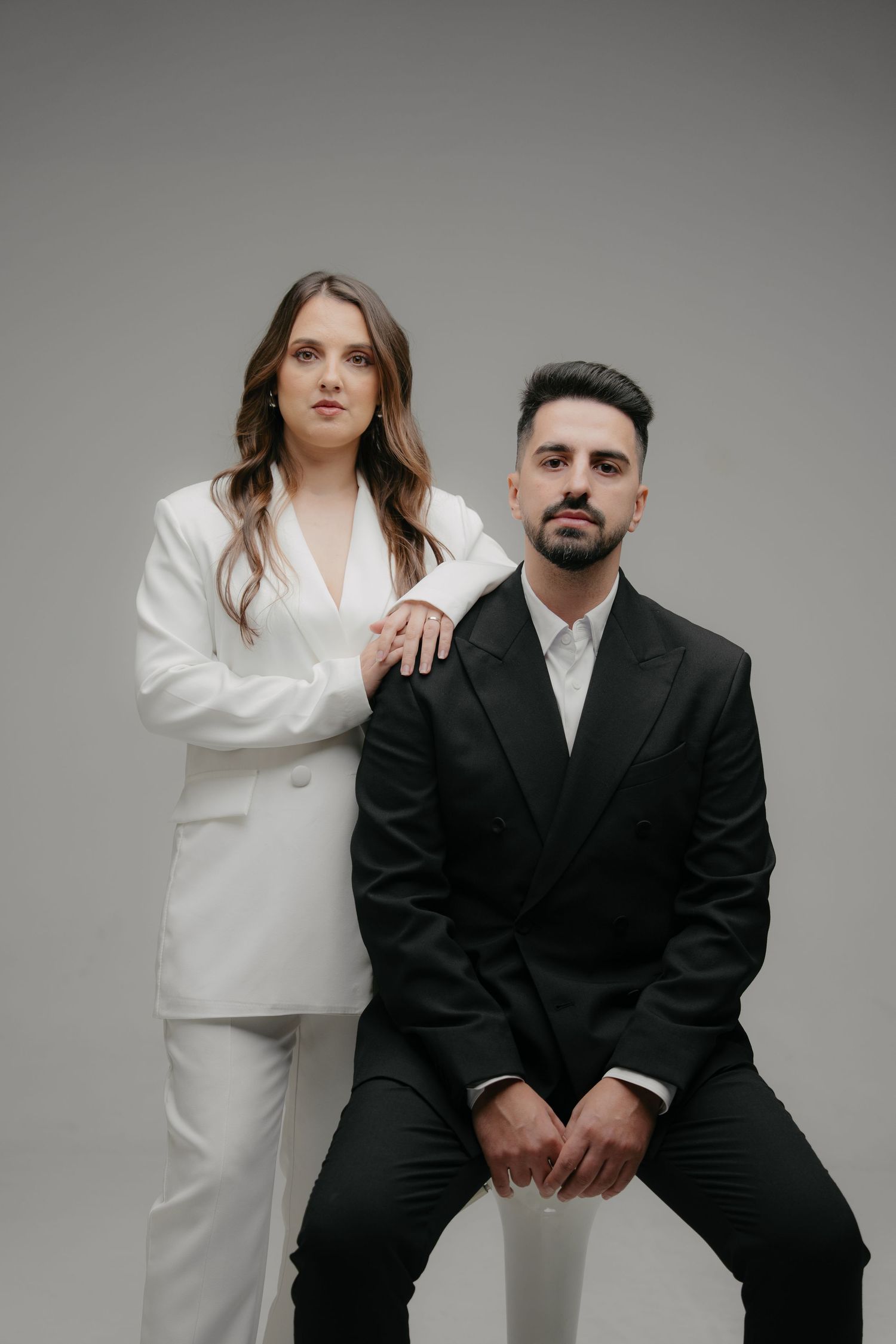 A fashion photo series showing contrasting black and white outfits in professional studio lighting against a gray backdrop.