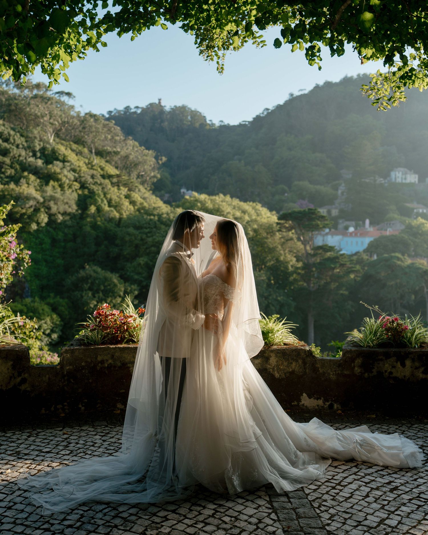 A romantic wedding photo series showing flowing white dresses and veils silhouetted against a mountainous landscape at sunset.