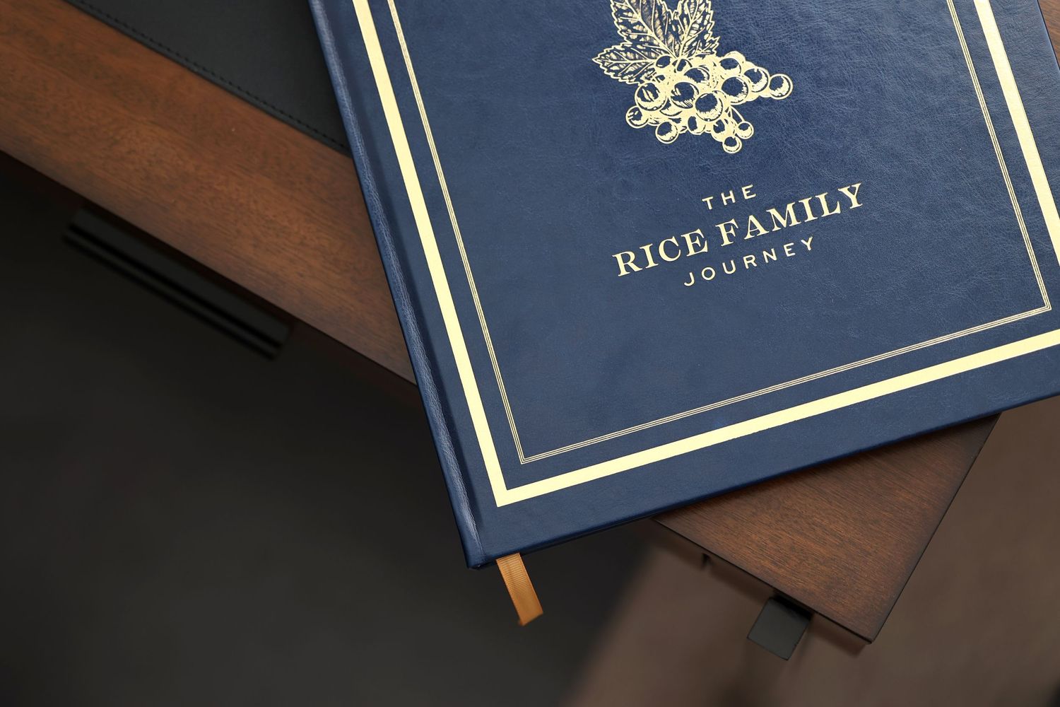 Elegant navy blue hardcover Rice Family Journey book with gold foil embossing on dark background.