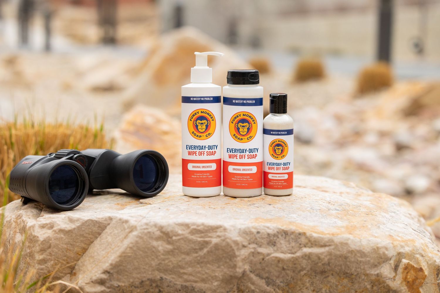 Bunky Monkey soap products displayed on a rock outdoors with binoculars nearby.