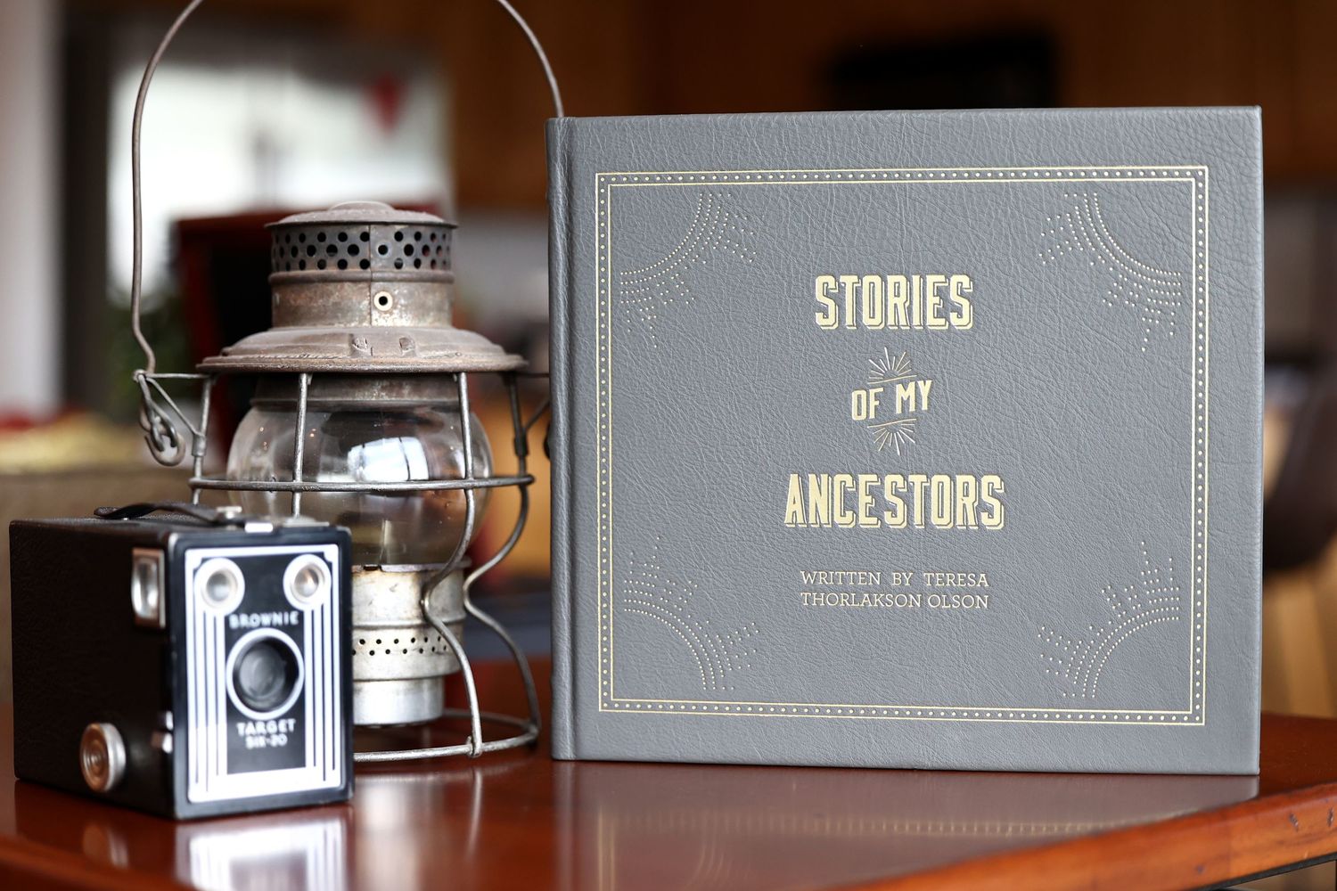 Stories of My Ancestors hardcover book displayed beside vintage lantern and antique camera.