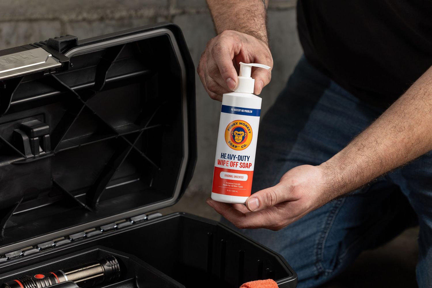 Man holding a pump bottle of heavy-duty hand soap over an open toolbox.