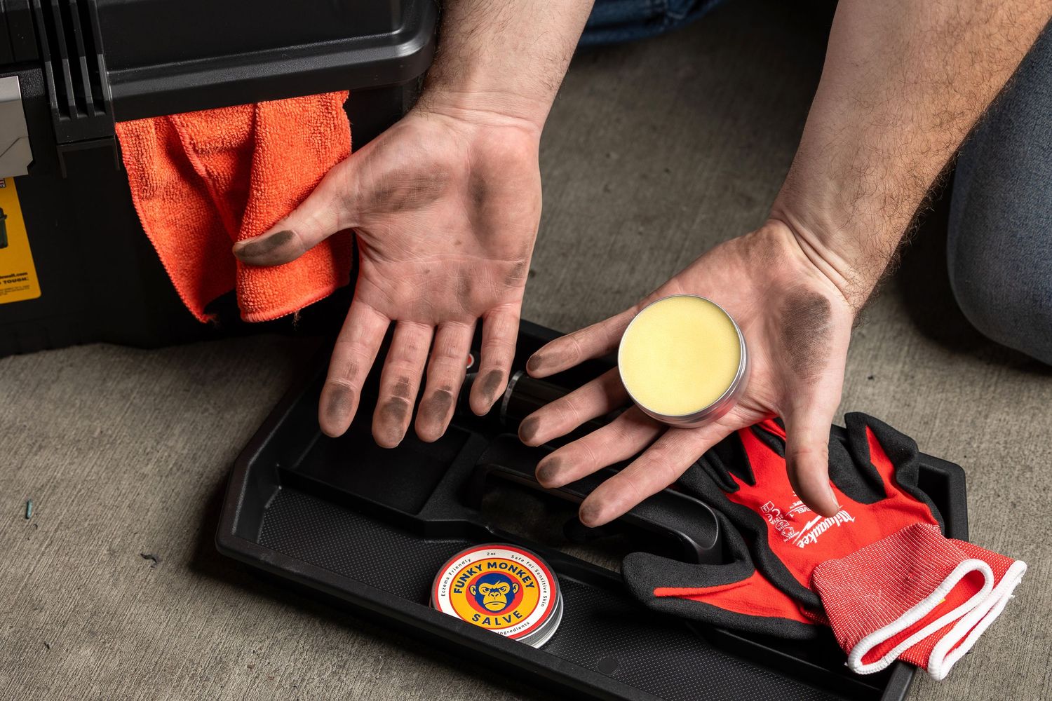 Mechanic with dirty hands holding a solid soap bar over a toolbox tray.