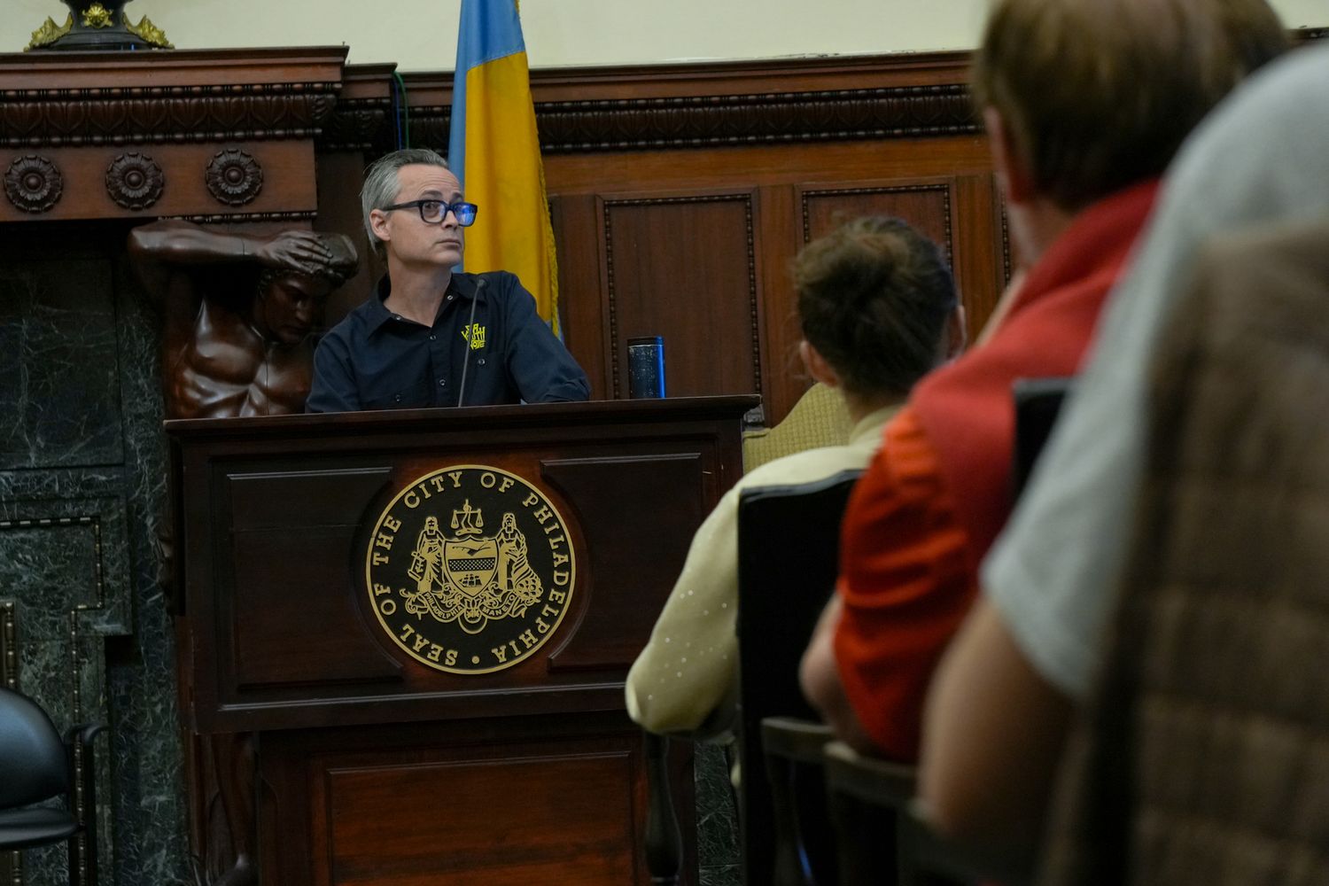 Speaker at a podium with Pennsylvania state seal addressing an audience indoors.
