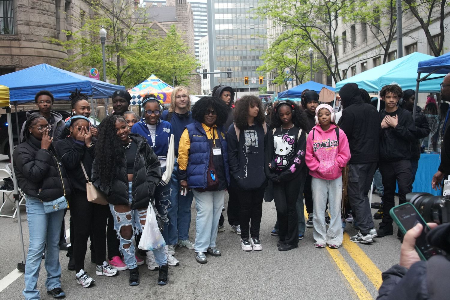 Large group of teens and young adults pose together at an outdoor street festival event.