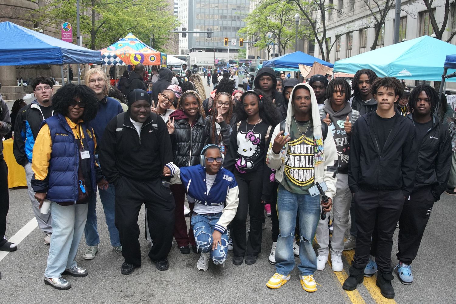 Diverse group of young people smile together at a colorful outdoor urban street fair.