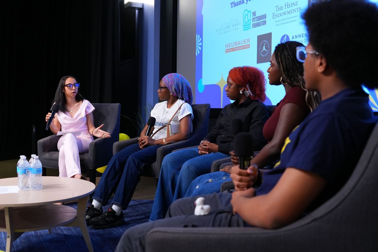 Panel discussion with diverse youth and moderator on stage at an educational forum event.