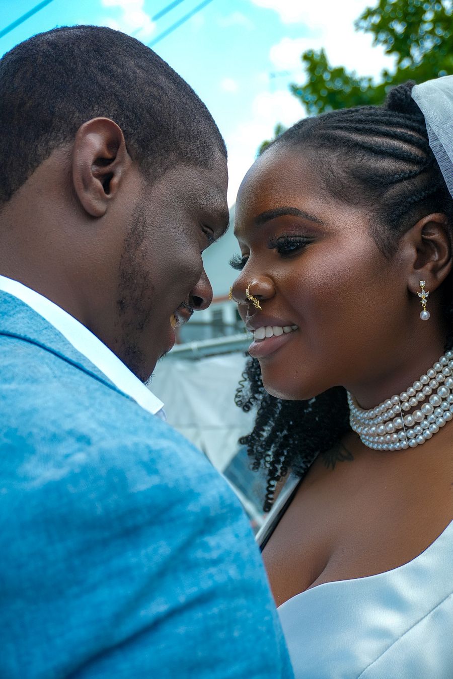 Joyful newlywed couple sharing an intimate forehead-to-forehead moment outdoors on their wedding day.