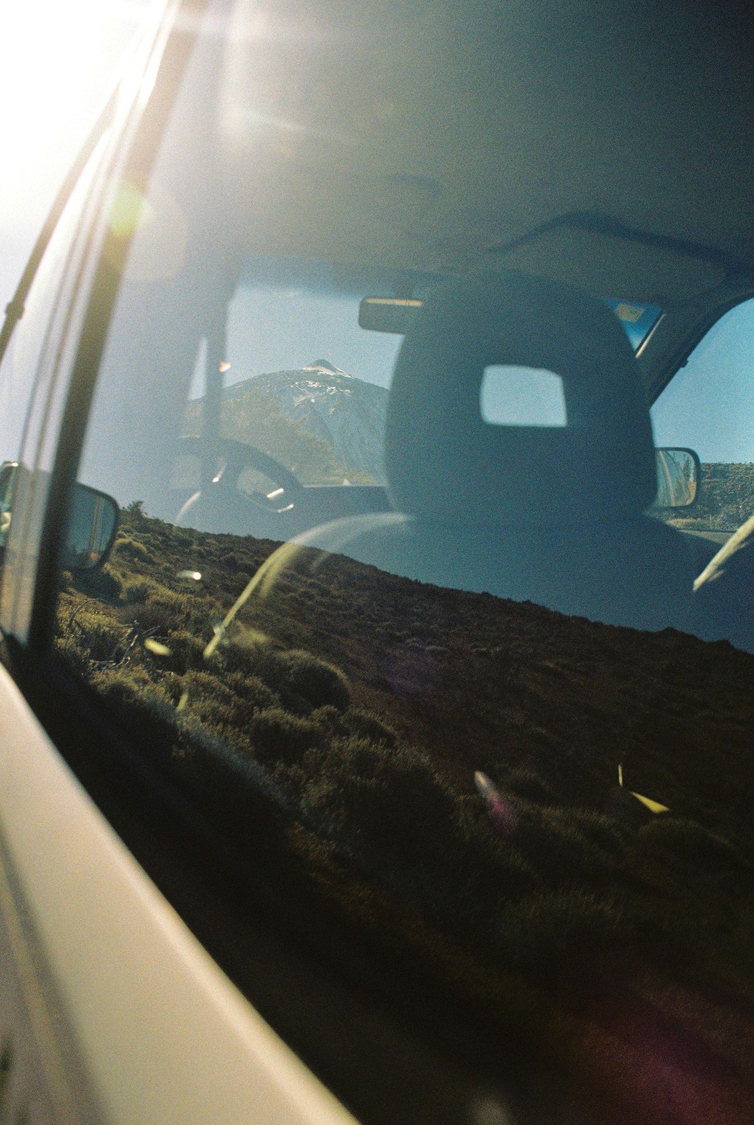 View of desert landscape through car window with sun flare.