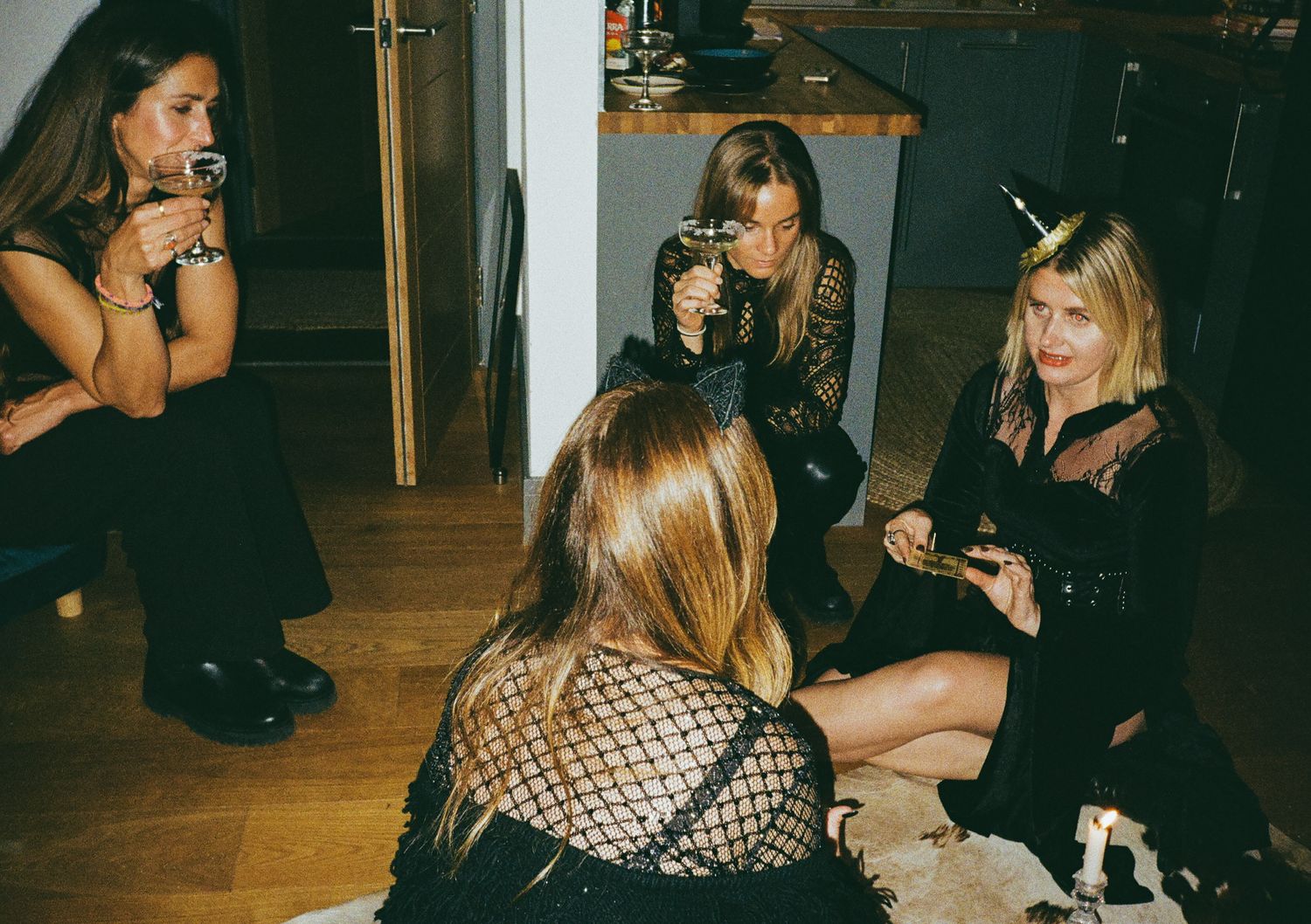 Group of friends enjoying a casual night gathering in dim lighting with drinks.