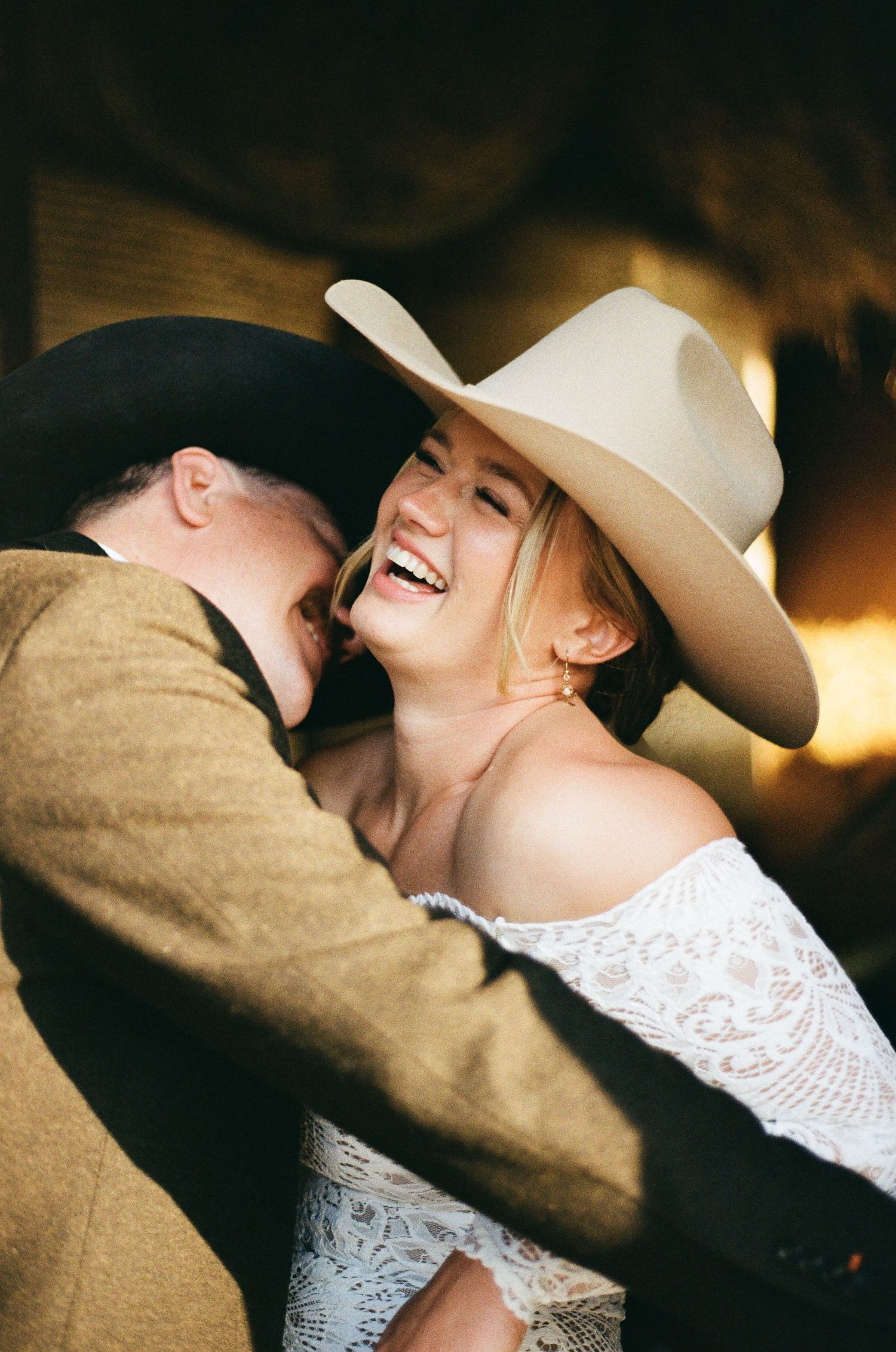 Intimate moment between couple wearing western attire and white hat.