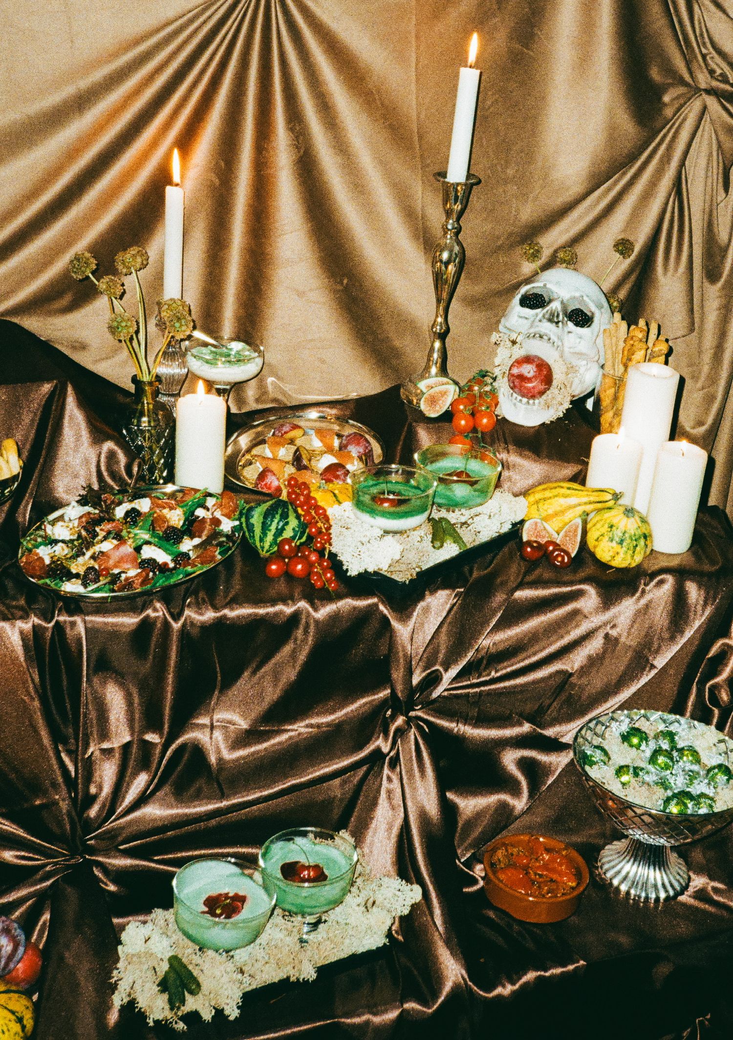 Elaborate Halloween party table with colorful treats, candles, and spooky decorative elements.