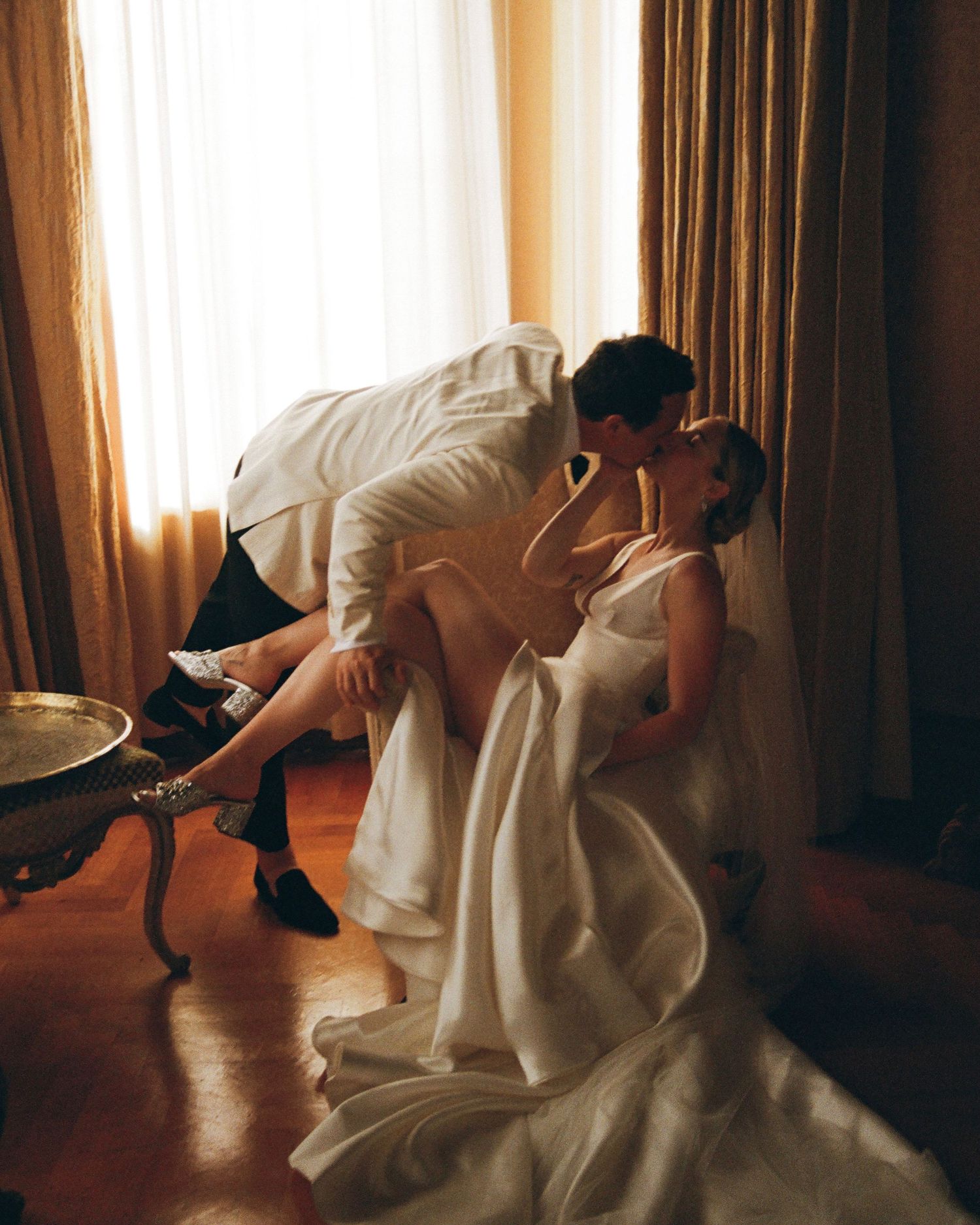 A wedding dress swirls gracefully during a dance in a sunlit room.