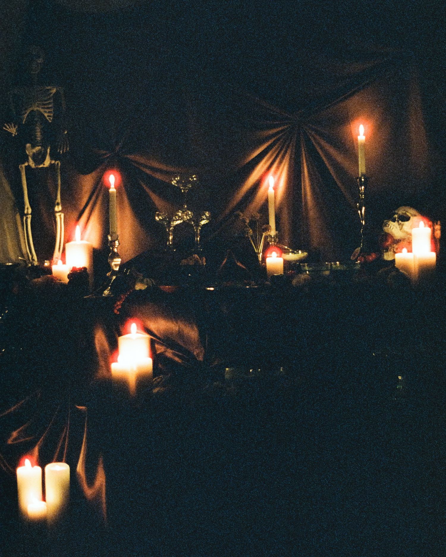 Lit candles create a moody atmosphere with dramatic shadows and warm glowing light against a dark background.