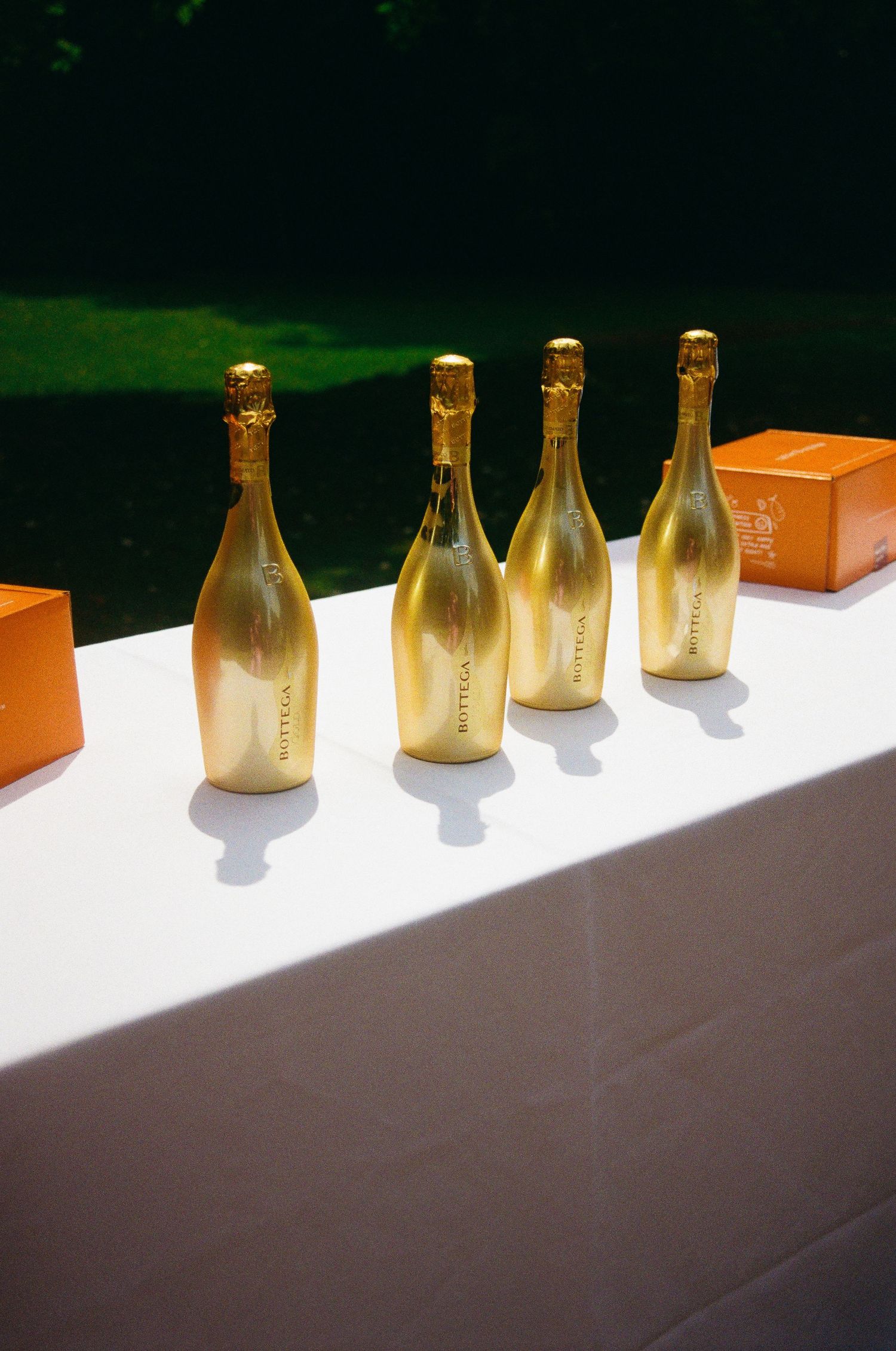 Line of gold champagne bottles displayed on white tablecloth.
