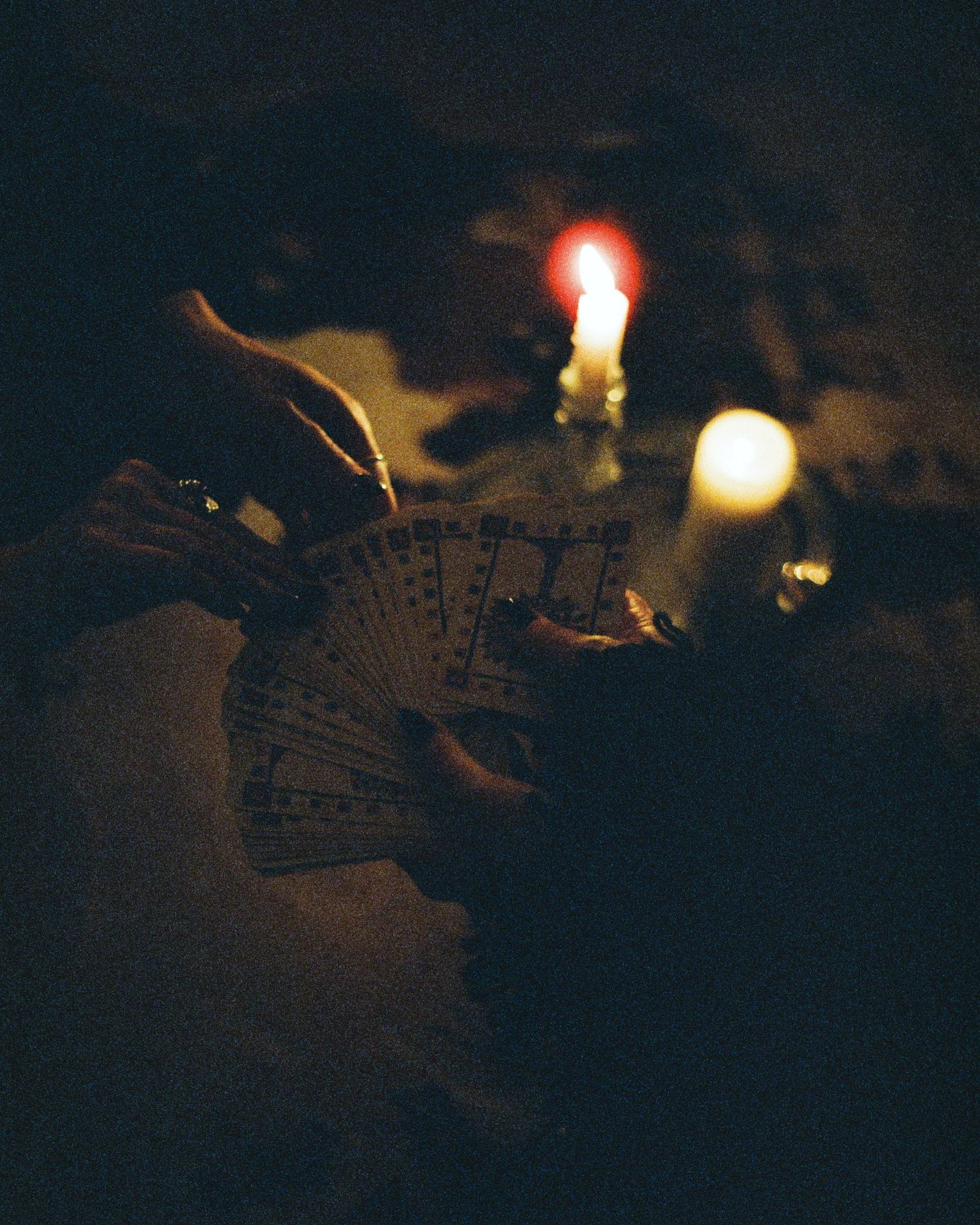 Playing cards illuminated by candlelight in a dark setting.