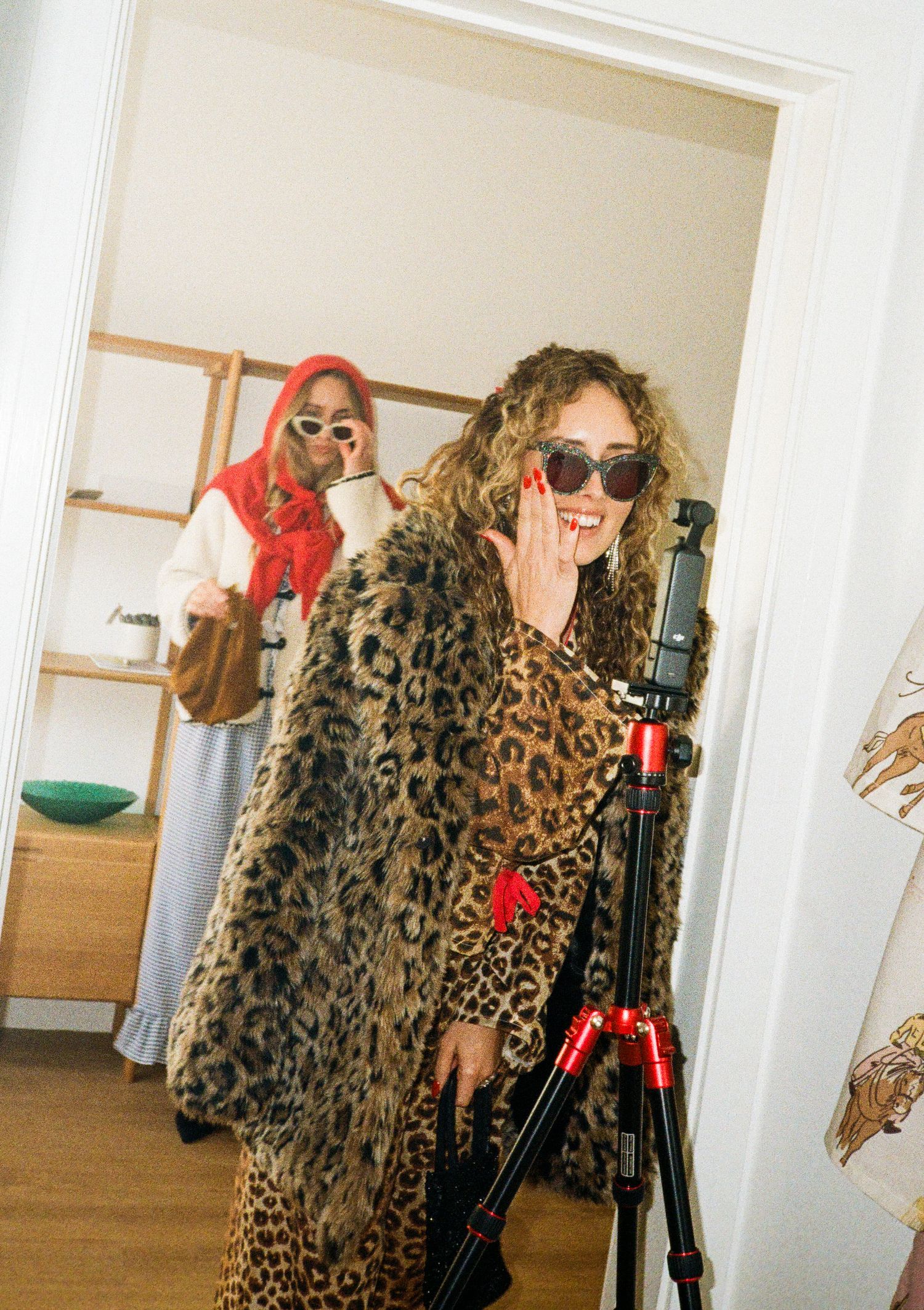 Fashion photography setup with leopard print coats and camera equipment in a bright room.