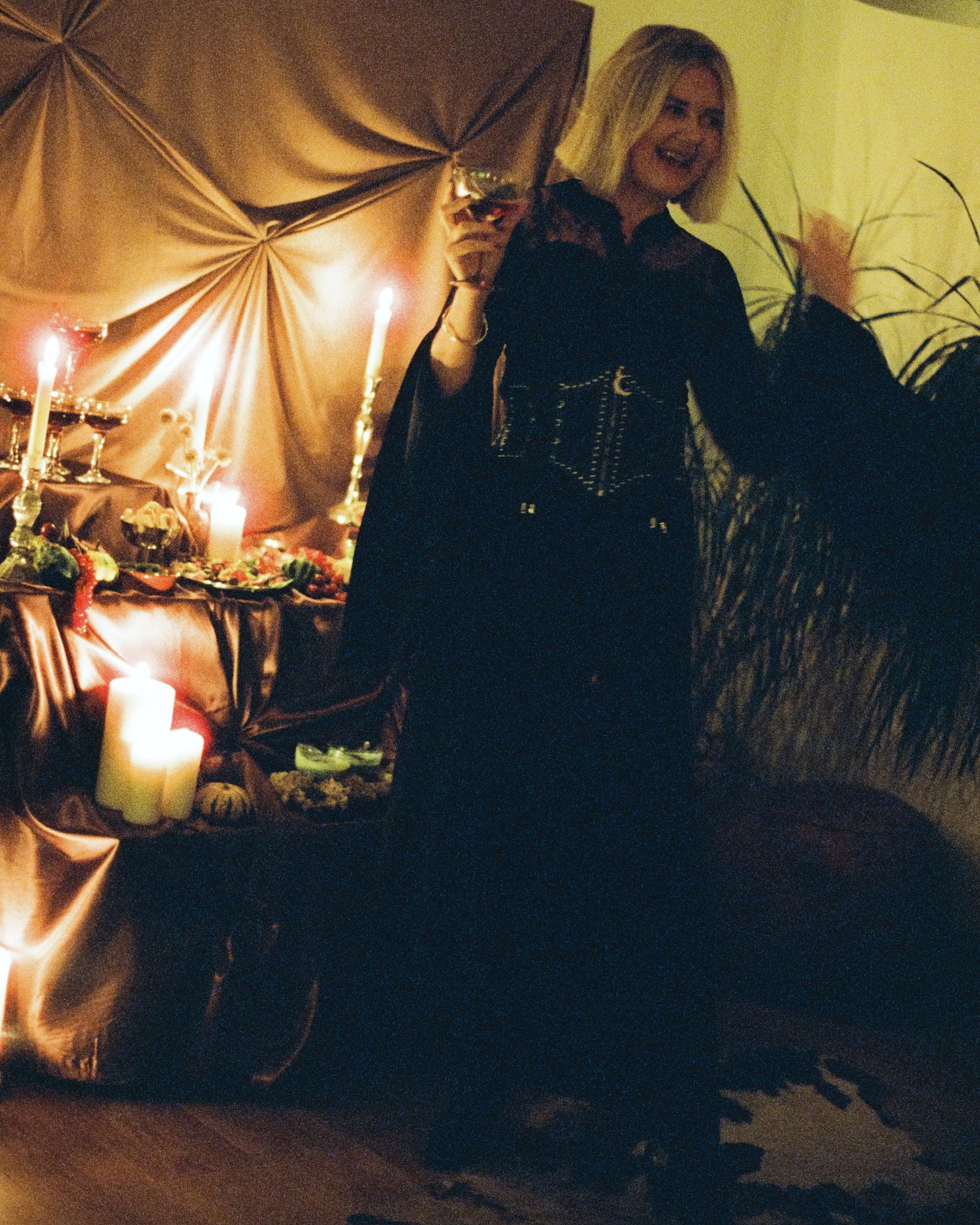A dimly lit gathering space with candles and fabric draping creating an intimate atmosphere.