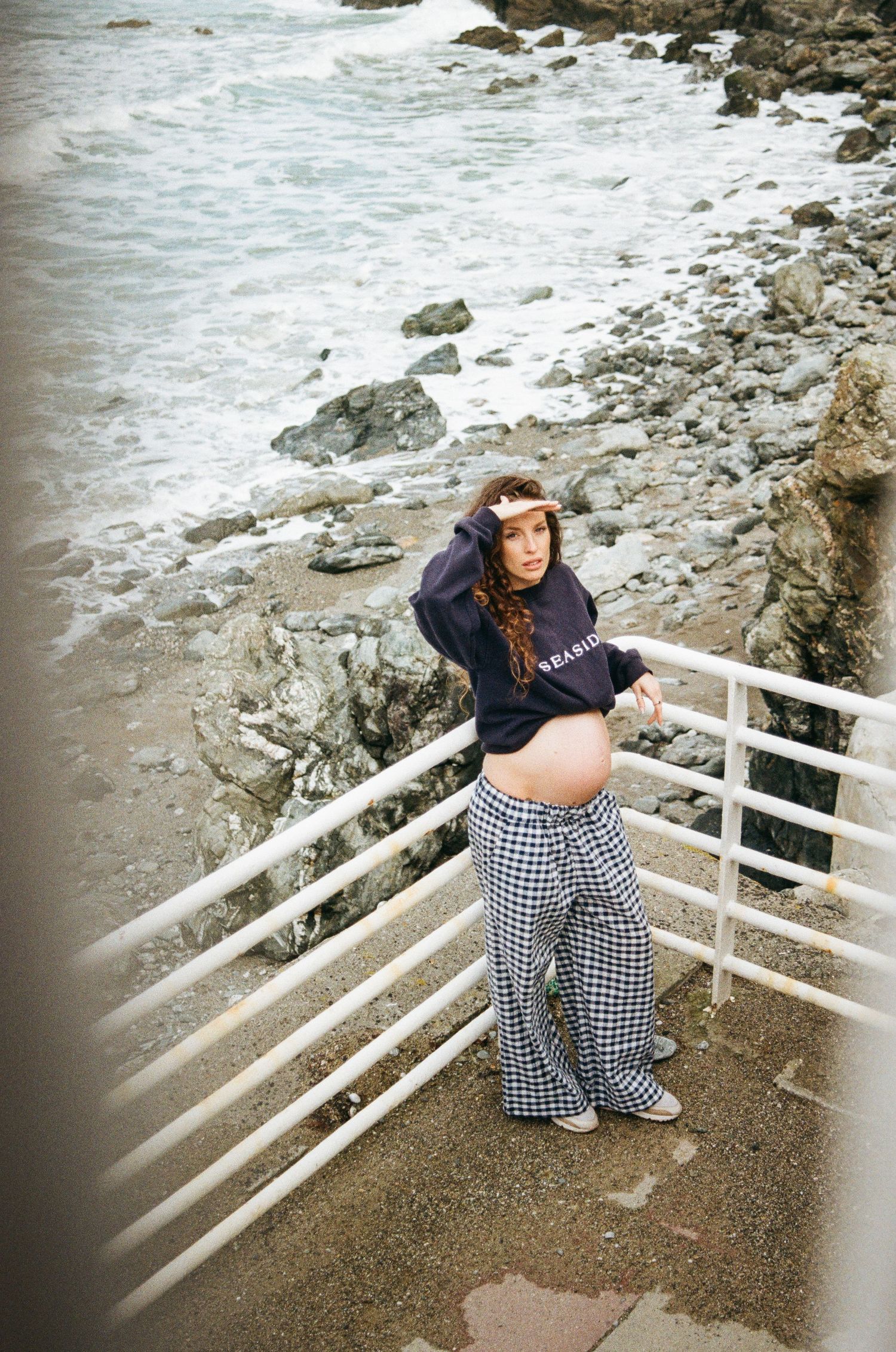 Seaside photos on a rocky beach with white railings and crashing waves in the background.
