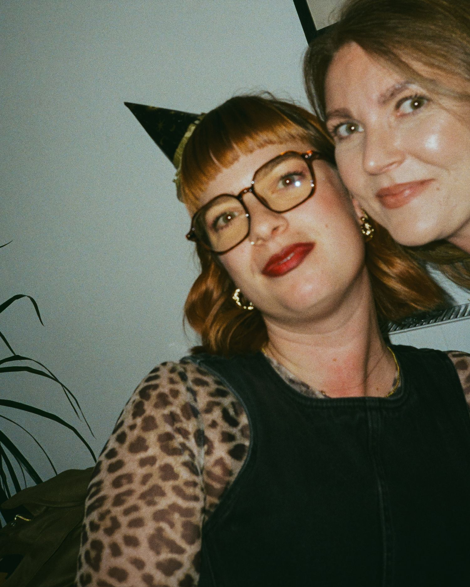 Friends in leopard print and dark clothing posing together at a party.