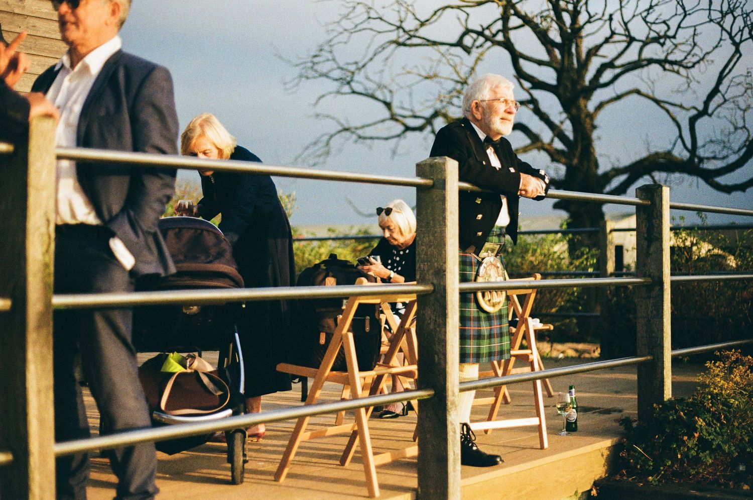 Wedding guests gather on an outdoor deck overlooking a scenic view.