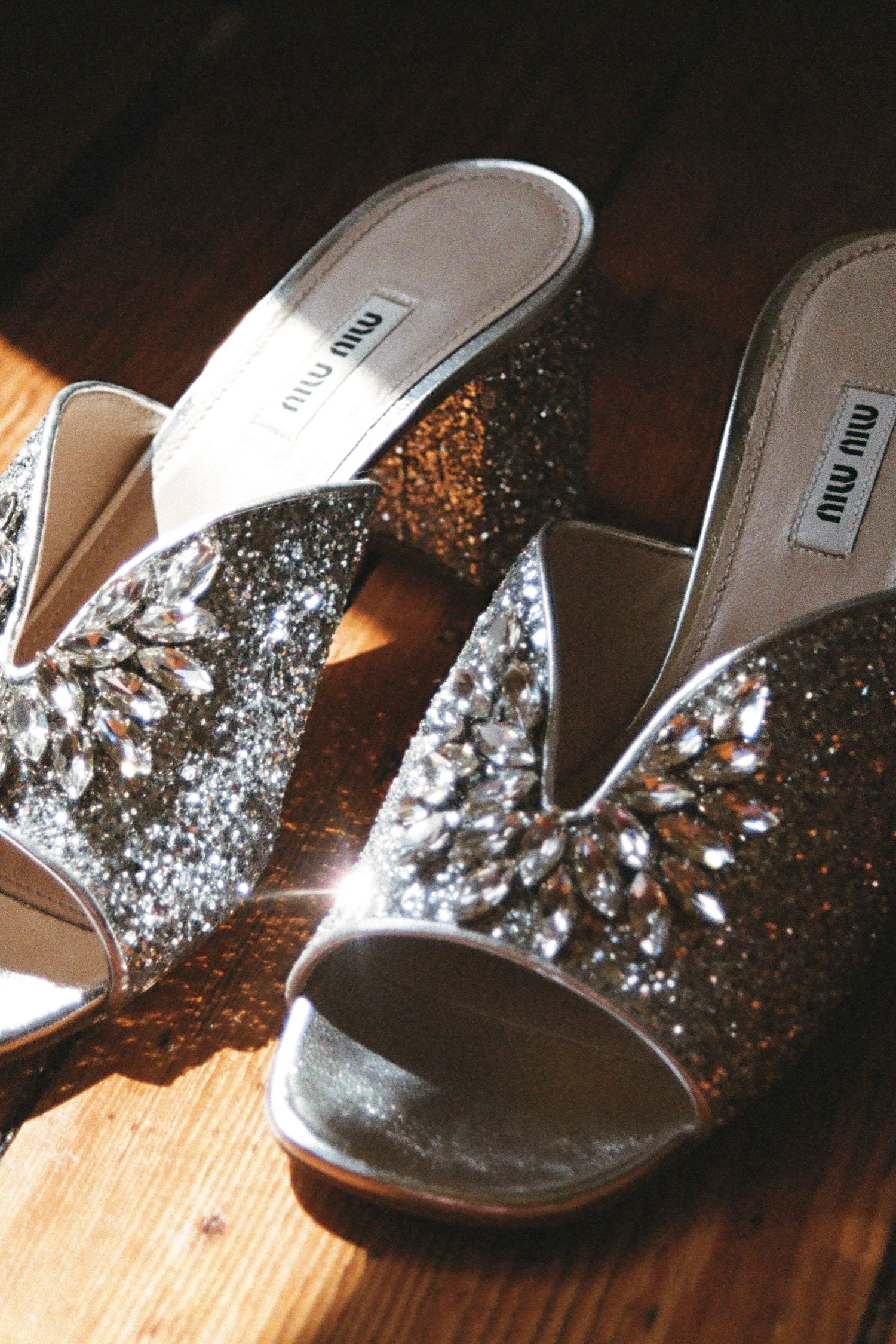 Sparkly silver wedding sandals displayed on wooden flooring.