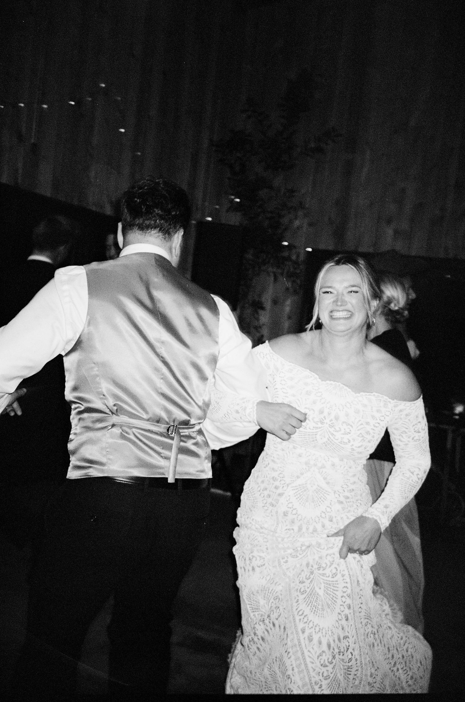 Wedding reception dance floor with couples celebrating in black and white photography.