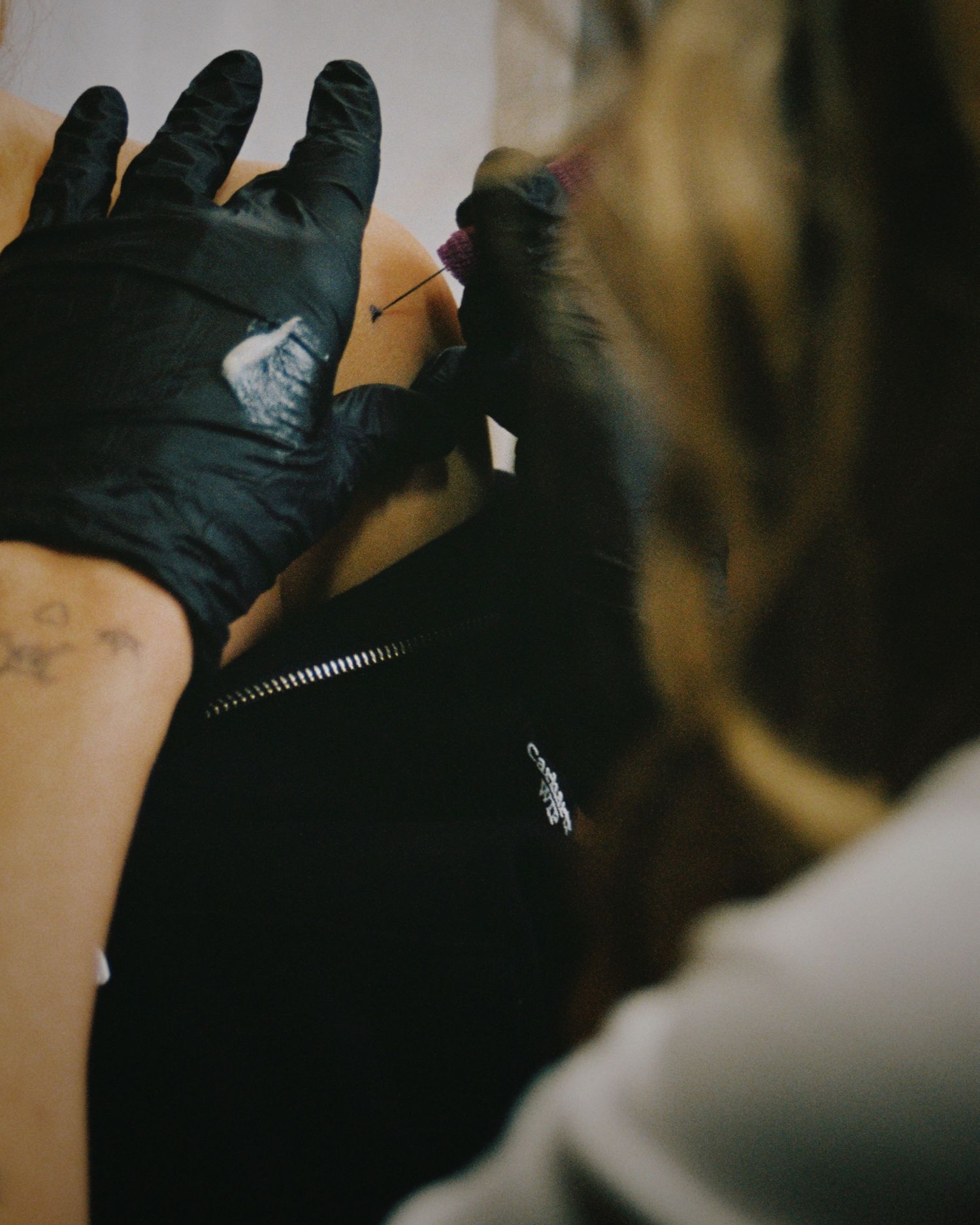Close-up view of hands wearing black gloves working with a zipper in dim lighting.