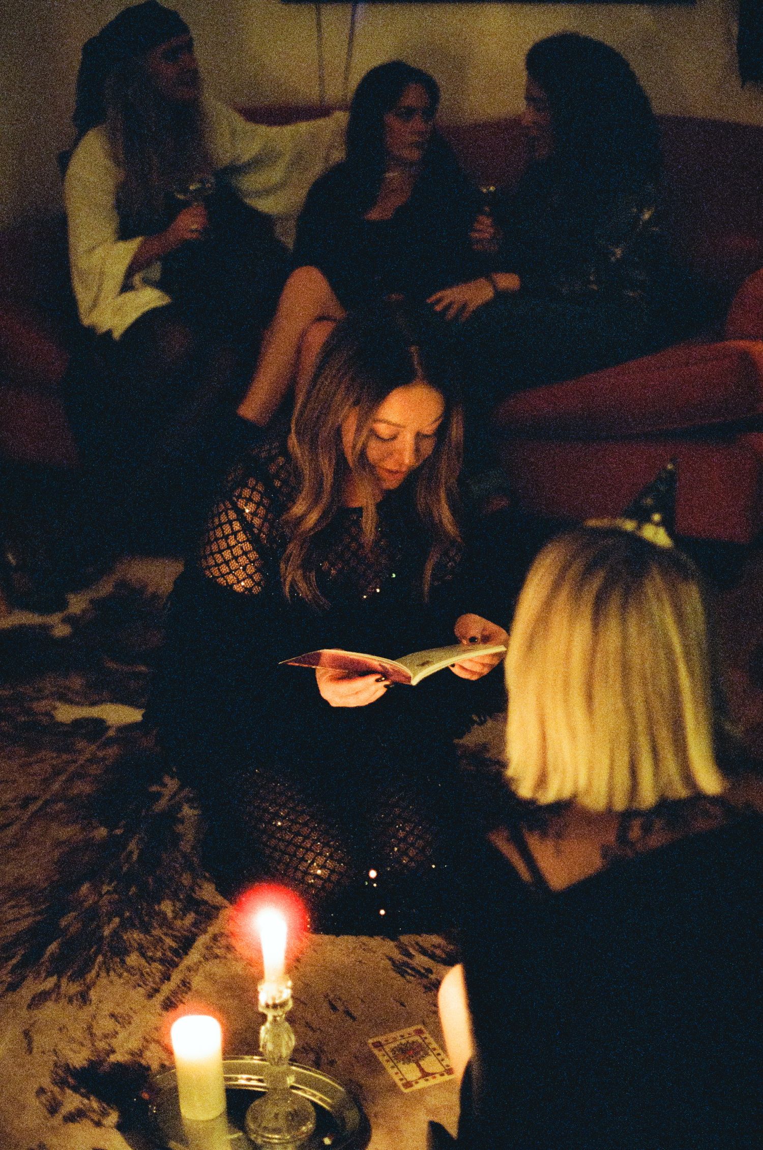 Halloween party scene with guests gathered around candlelit table.