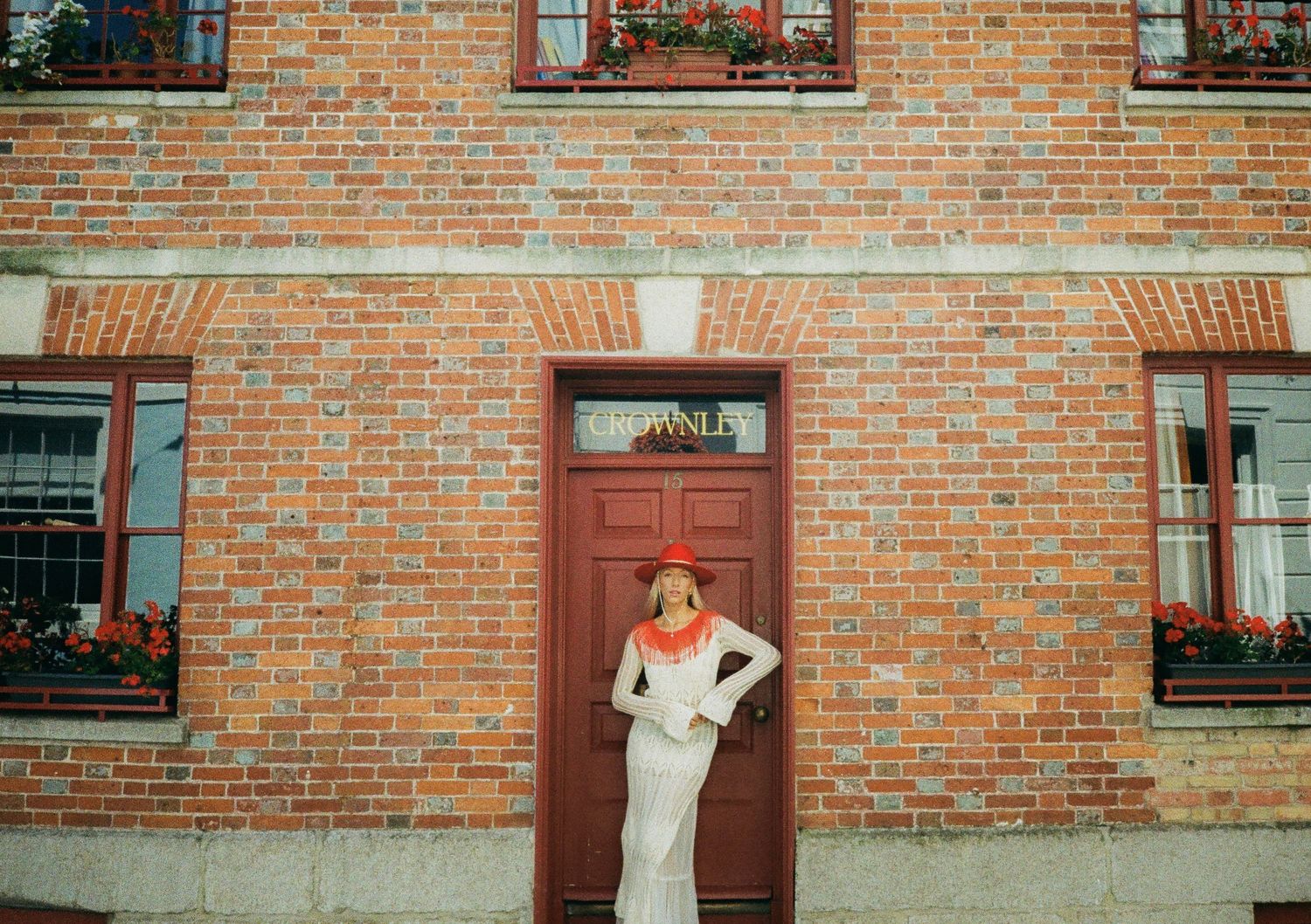 Panoramic view of a brick building exterior with red window boxes and flowers.