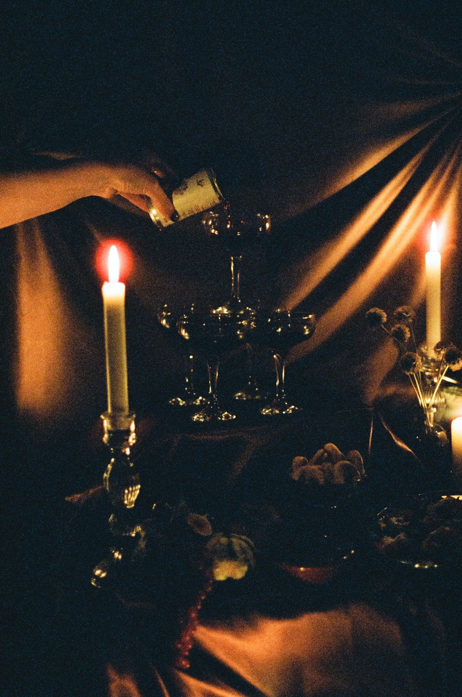 Dark and moody candlelit Halloween table setting with dramatic shadows.