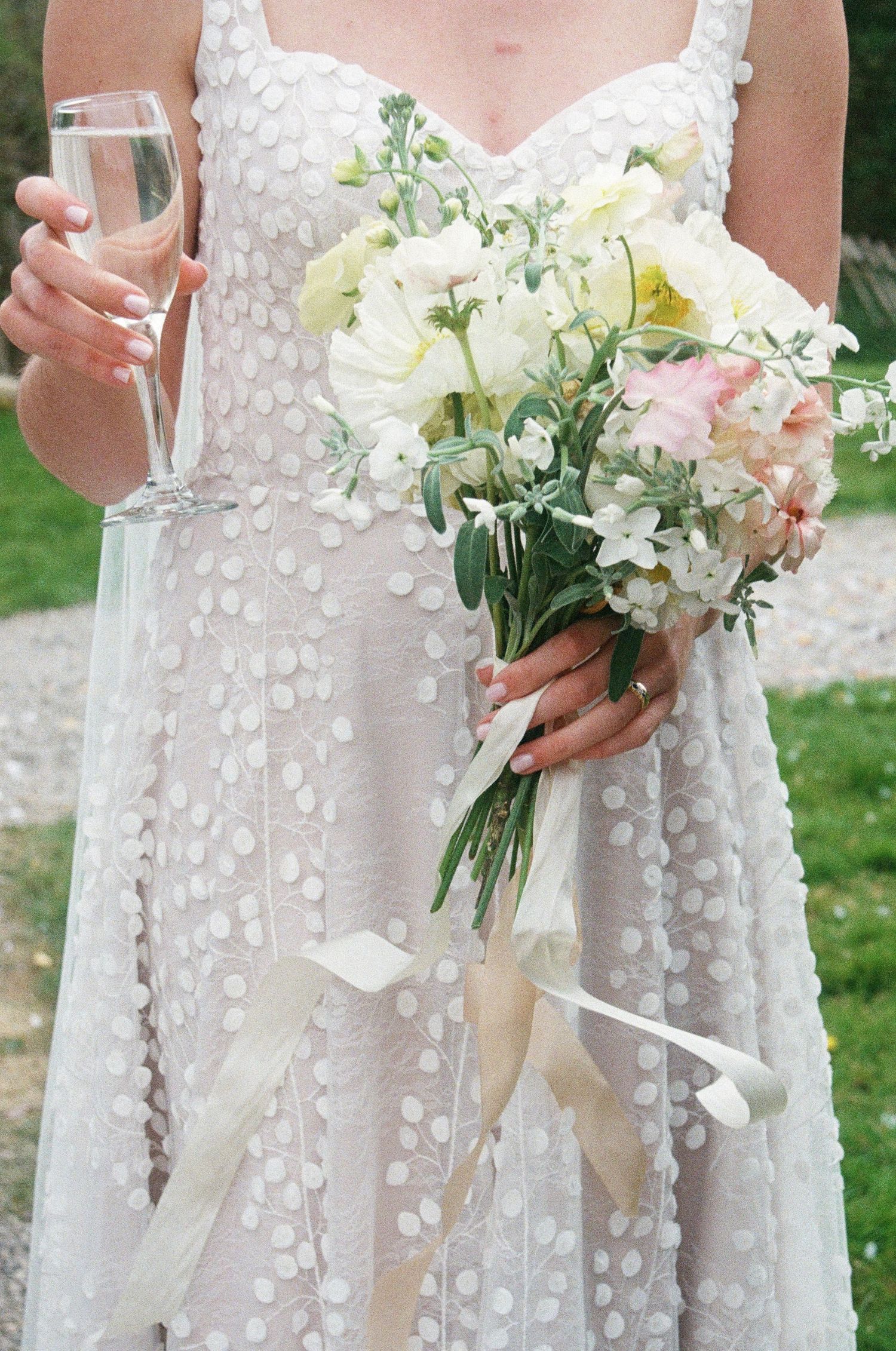 Elegant white wedding dress with floral appliques paired with delicate white bouquet.