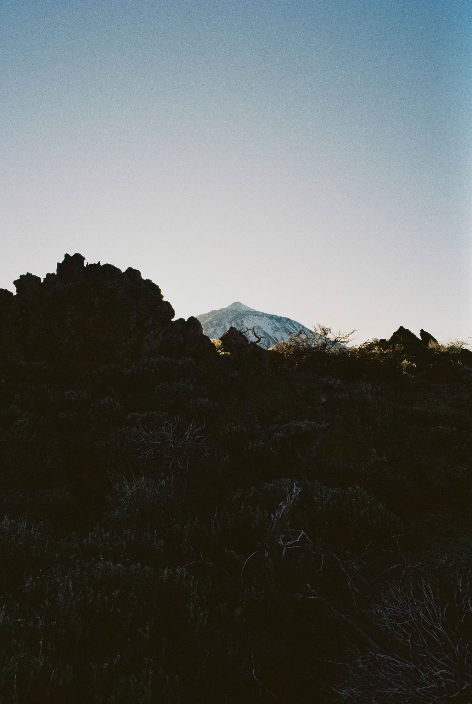 Mountain silhouette against fading blue sky at dusk.