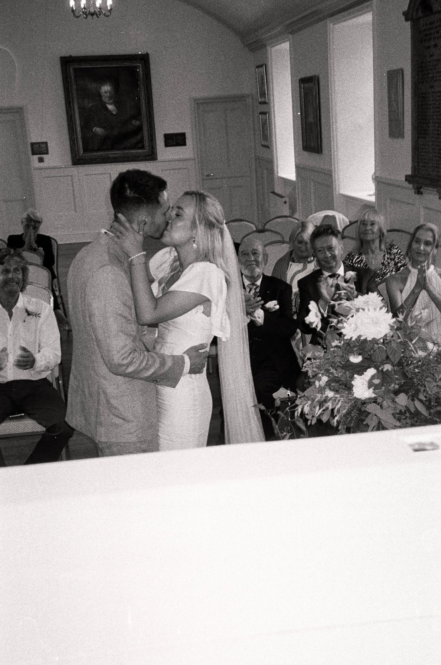 Black and white photo of wedding reception guests mingling in an elegant indoor venue.